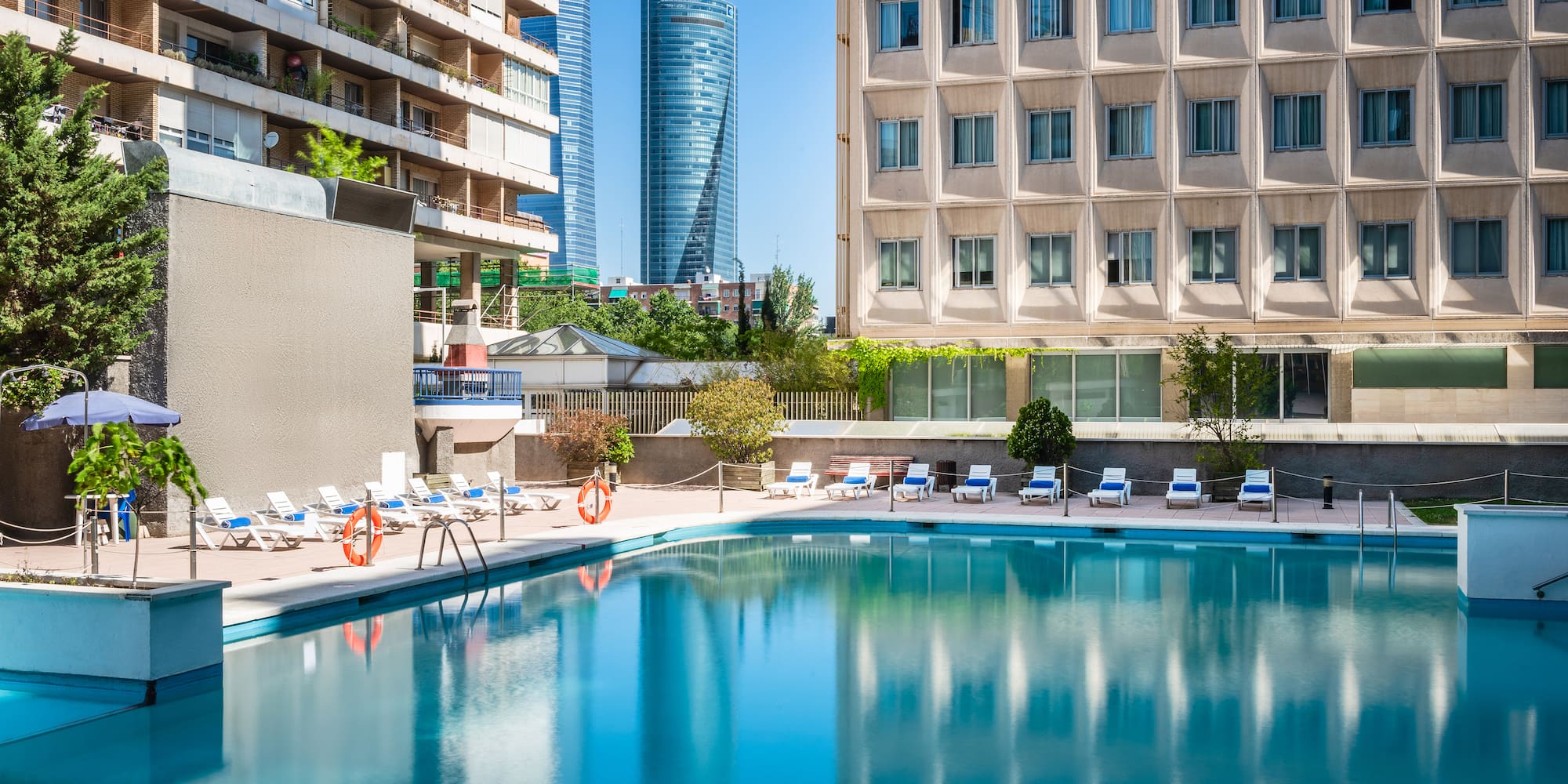 a pool with chairs and a building in the background