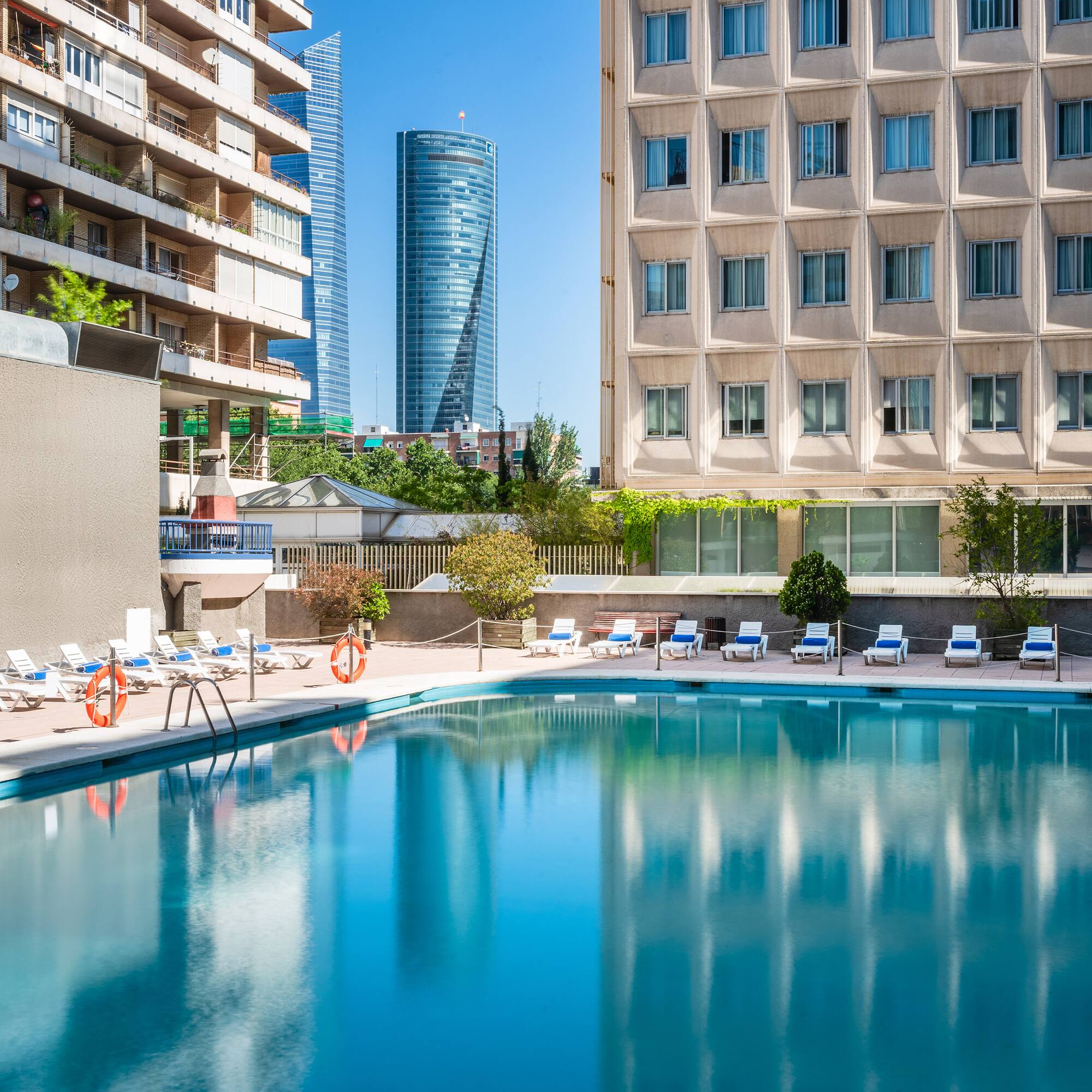 a pool with chairs and a building in the background