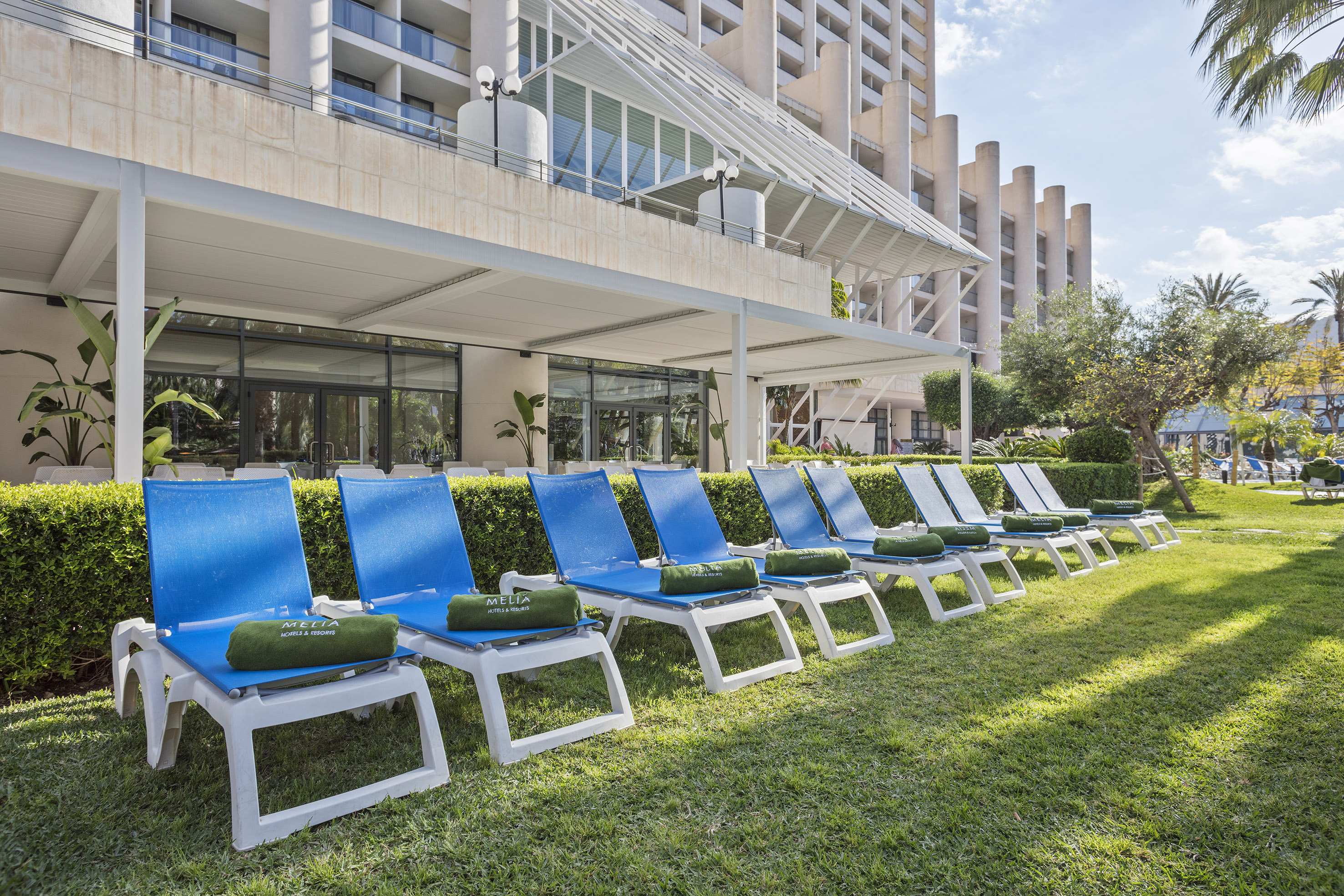 Meliá resort: row of blue sun loungers with green towels on a sunny lawn.
