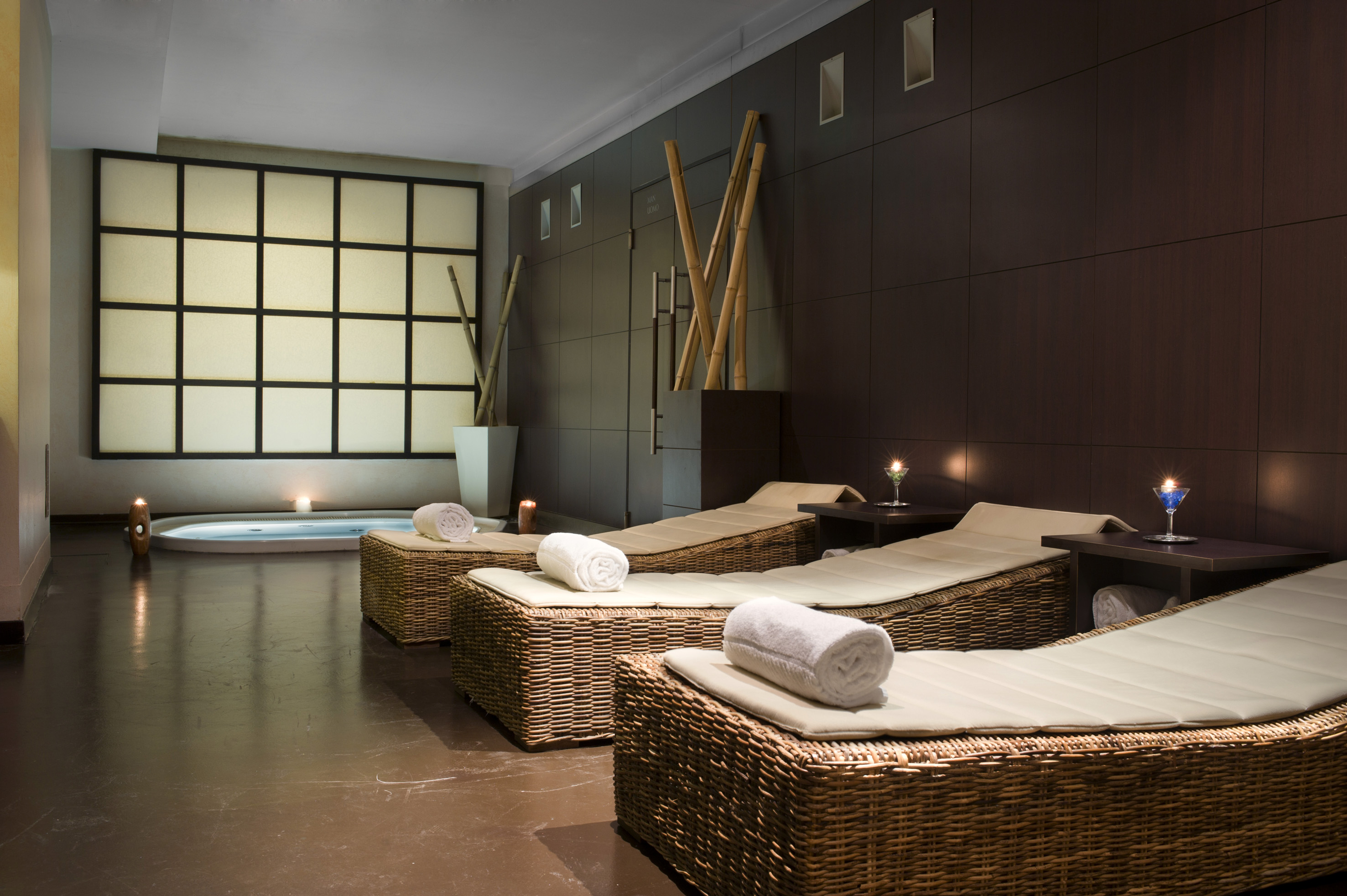 Serene spa lounge with jacuzzi, wicker lounge chairs, bamboo, and ambient lighting.
