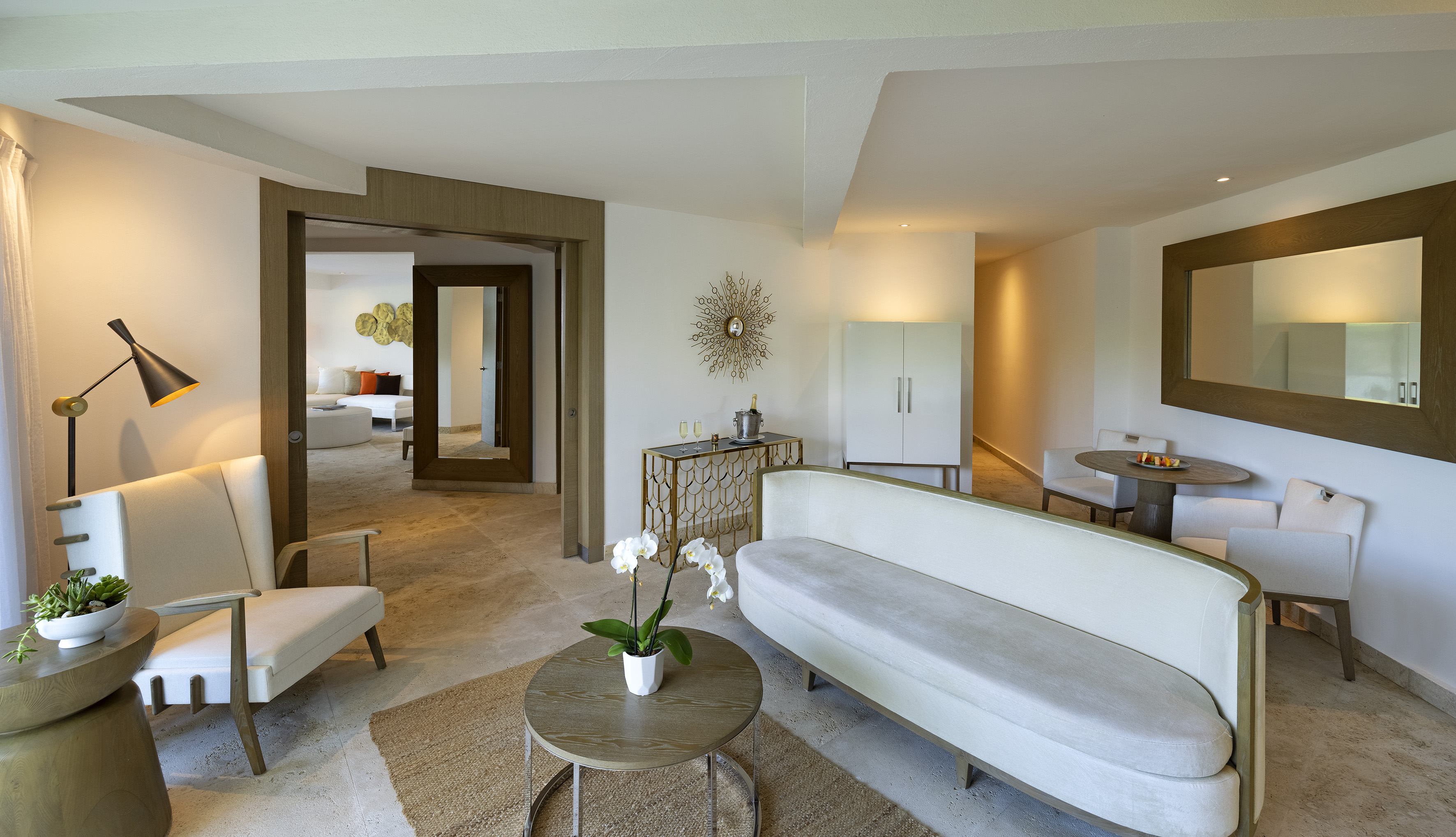 Modern luxury suite living room with neutral decor and dining area.