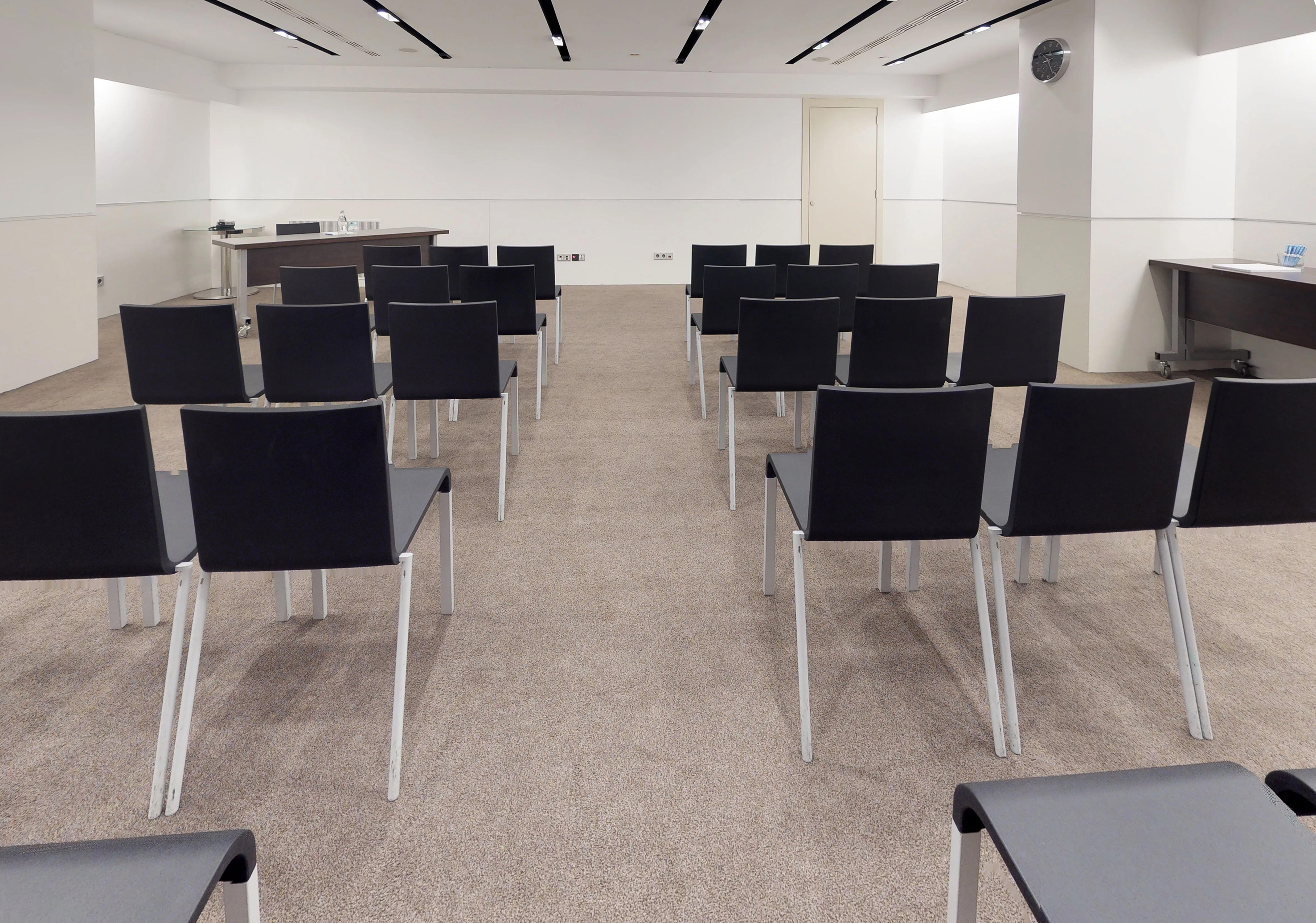 Empty modern conference room with black chairs and a front presentation table.