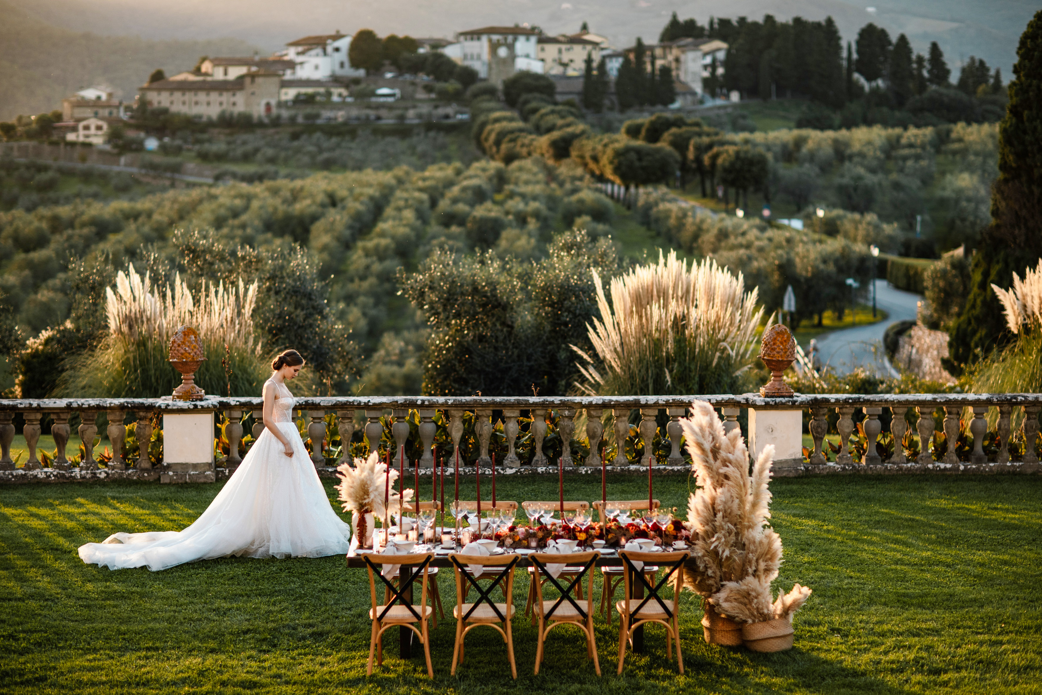 Elegant bride at outdoor Tuscan wedding reception, decorated table, golden hour.