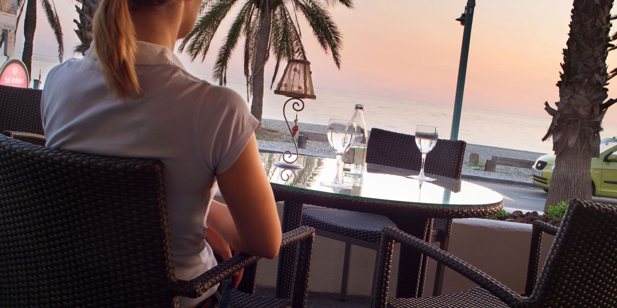 a woman sitting at a table overlooking a beach