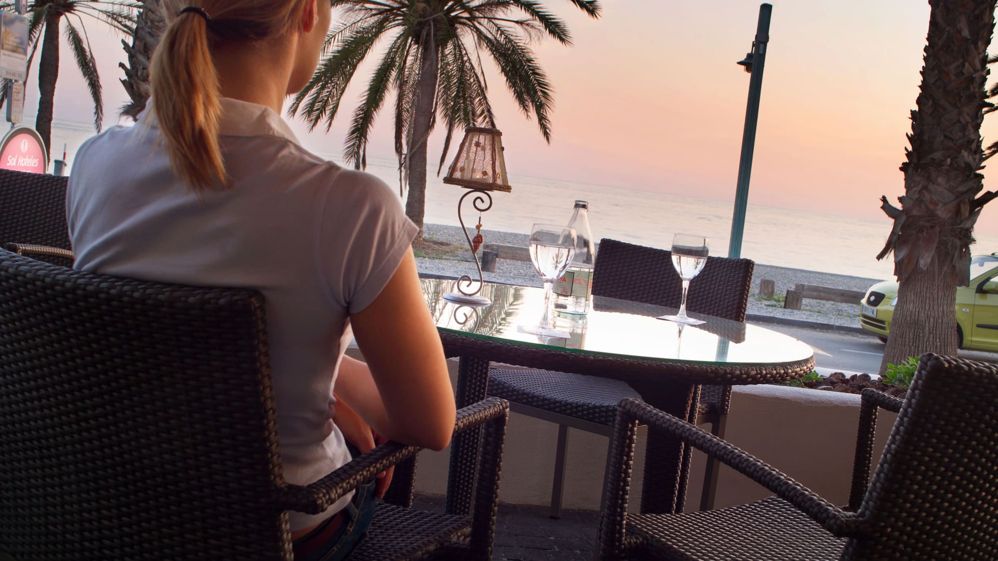 a woman sitting at a table overlooking a beach