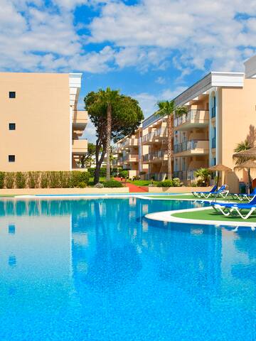 a pool with chairs and a building in the background