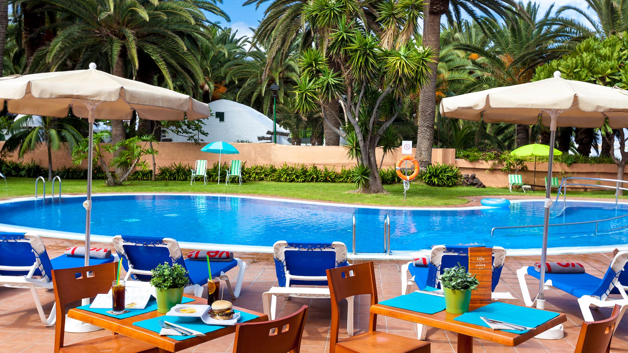 a pool with tables and chairs and umbrellas