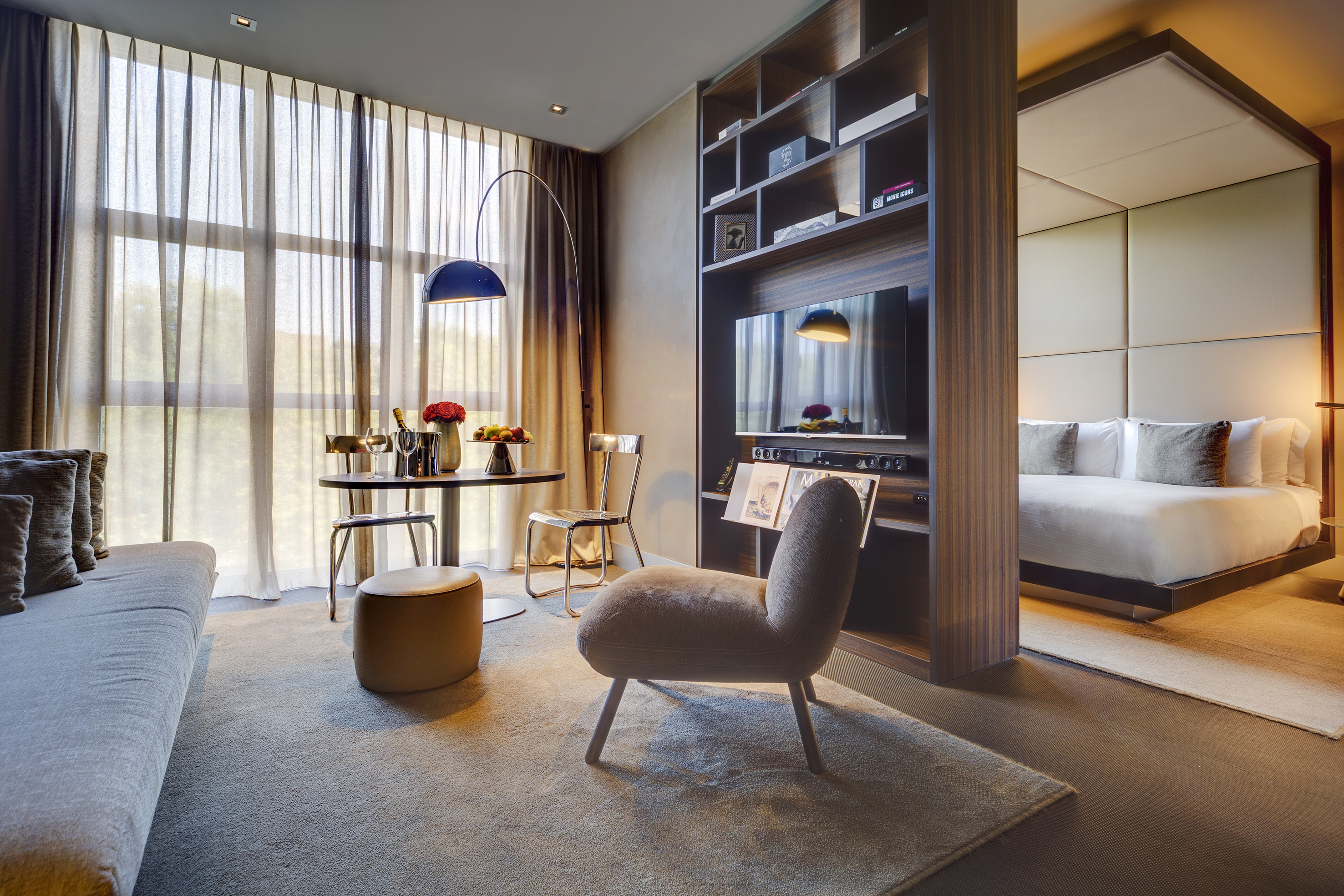 Luxurious modern hotel suite with separate living and sleeping areas.