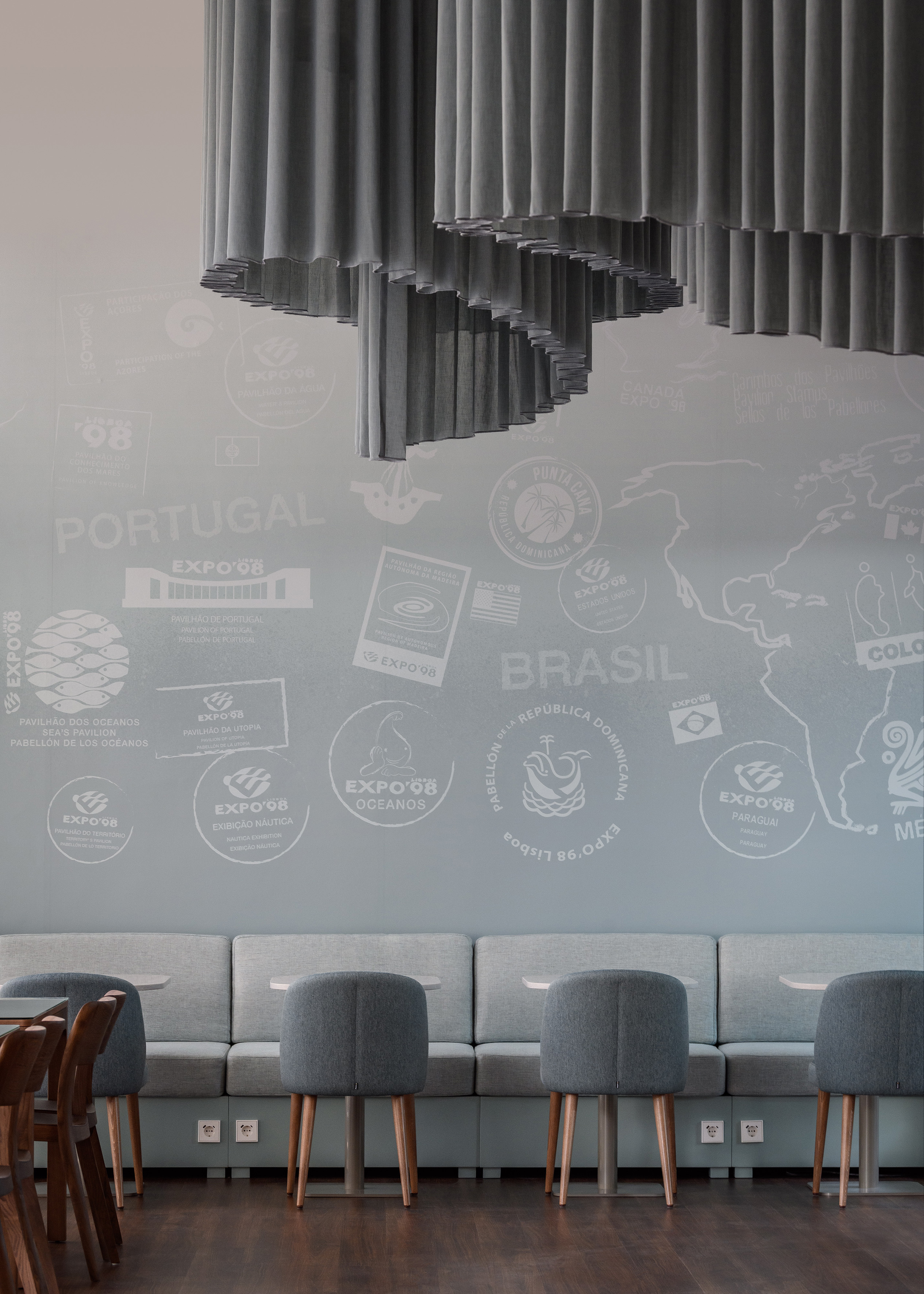 Modern cafe with Expo '98 wall graphics, wavy gray ceiling, and booth seating.