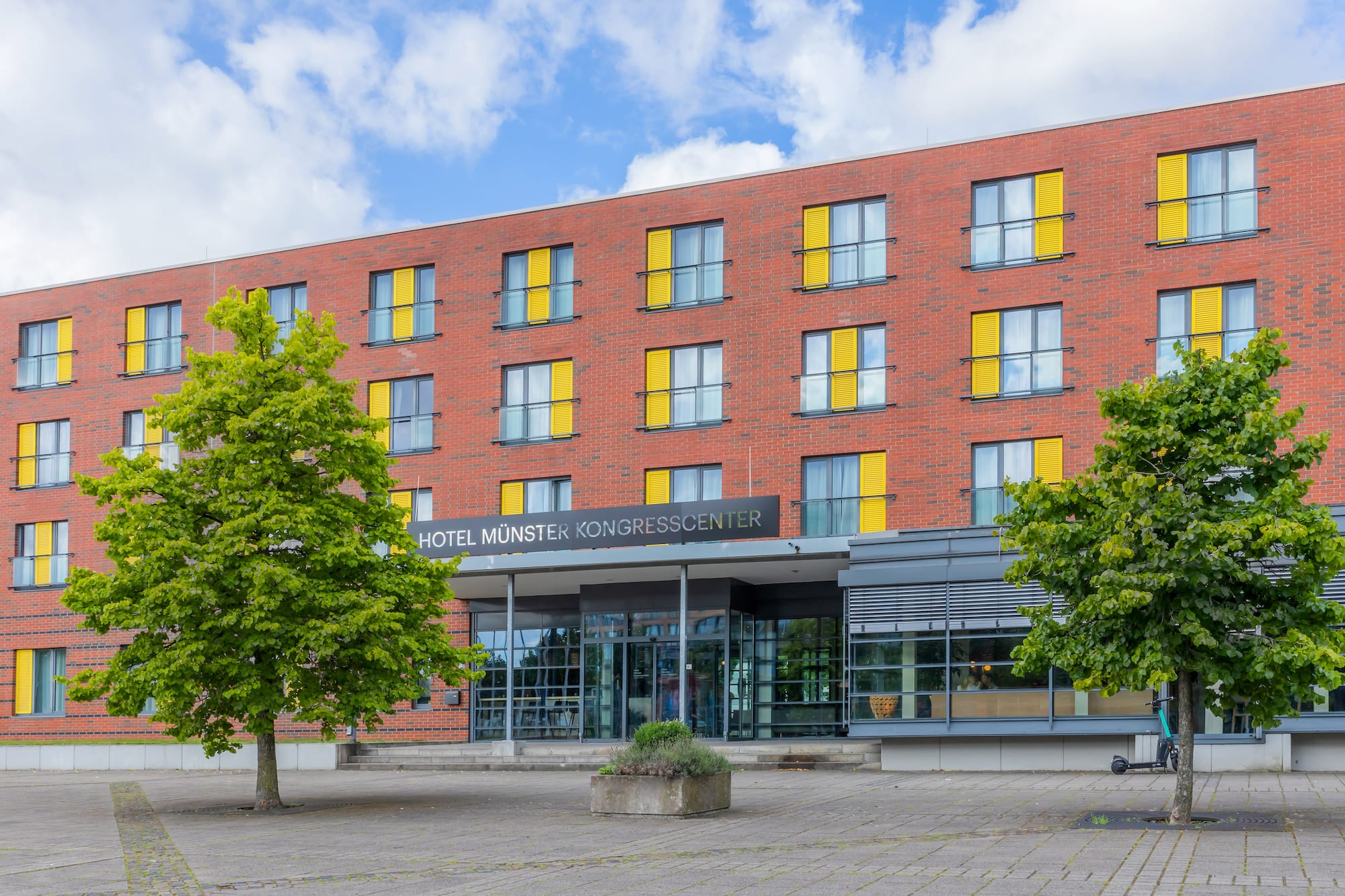 Hotel Münster Kongresscenter, red brick facade with yellow window shutters.