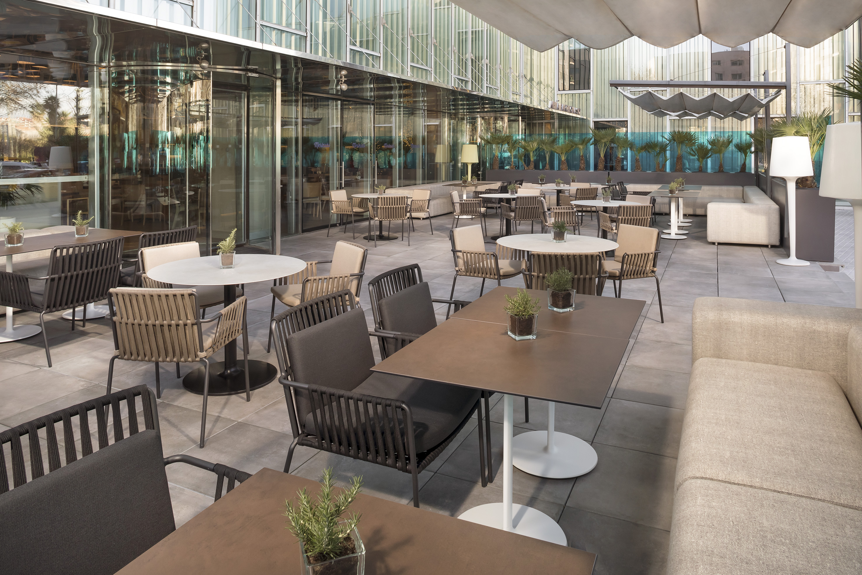 Modern hotel patio with outdoor dining tables, chairs, and lounge seating.