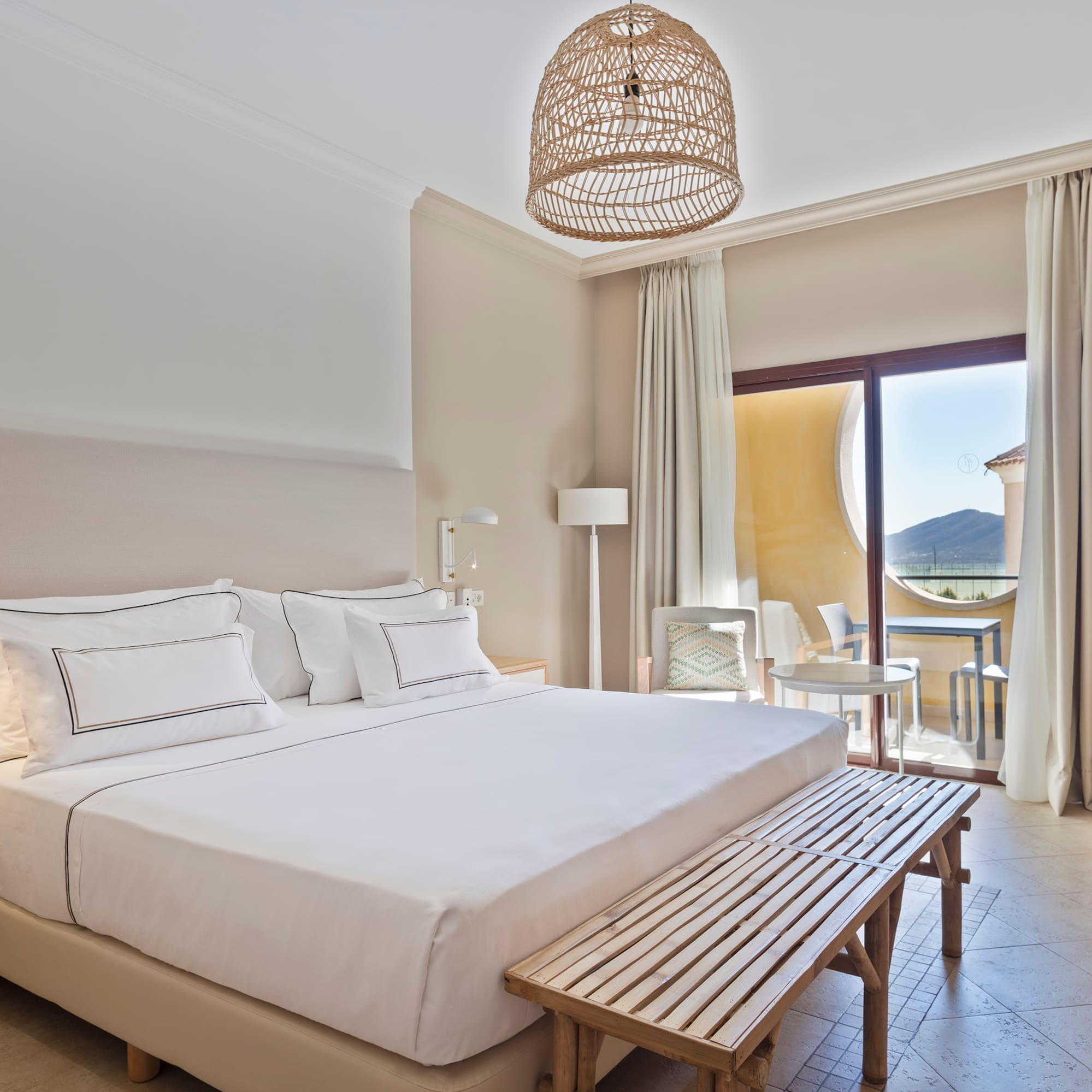 a bed with a bench and a table in a room with a balcony