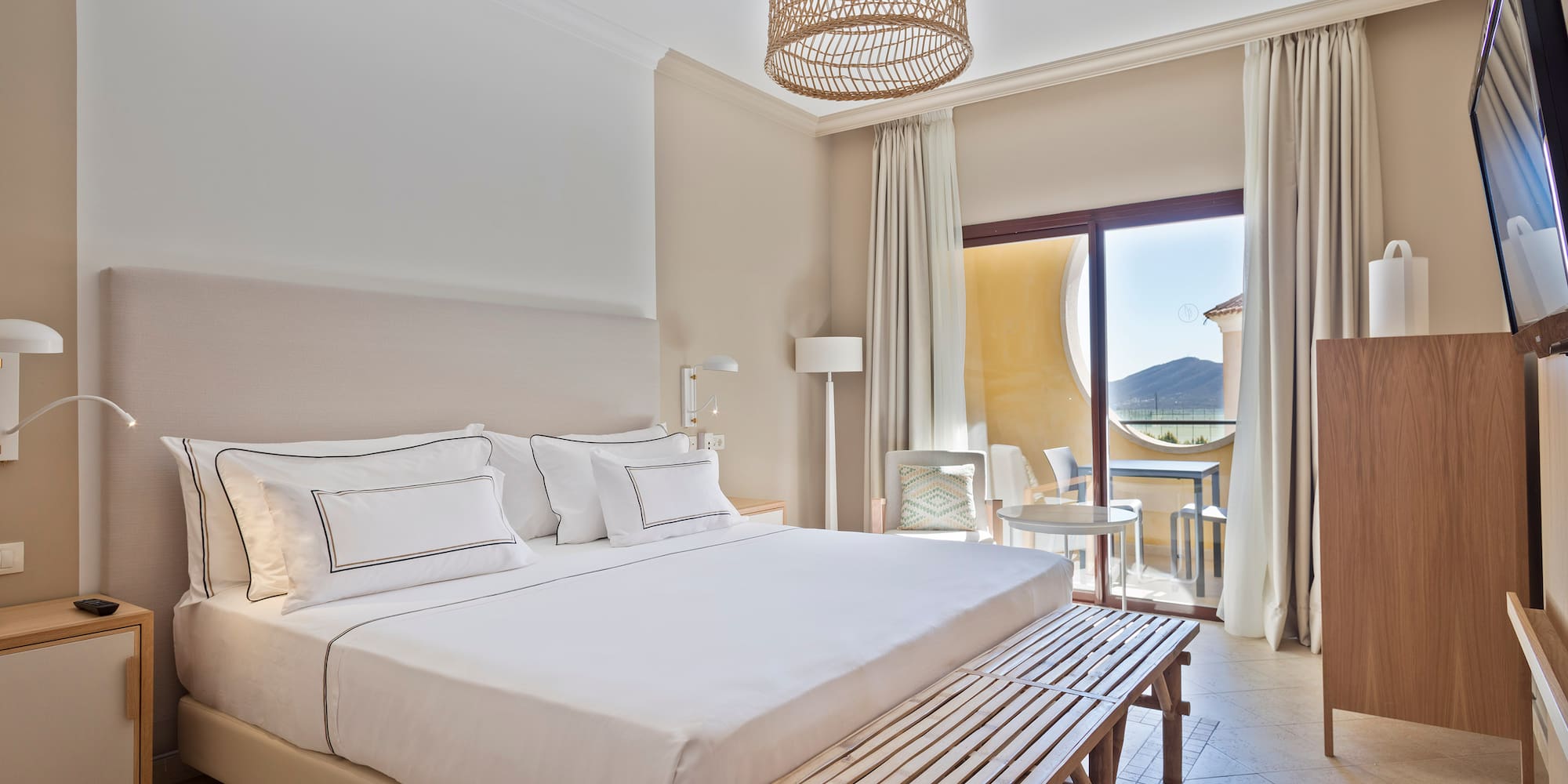 a bed with a bench and a table in a room with a balcony