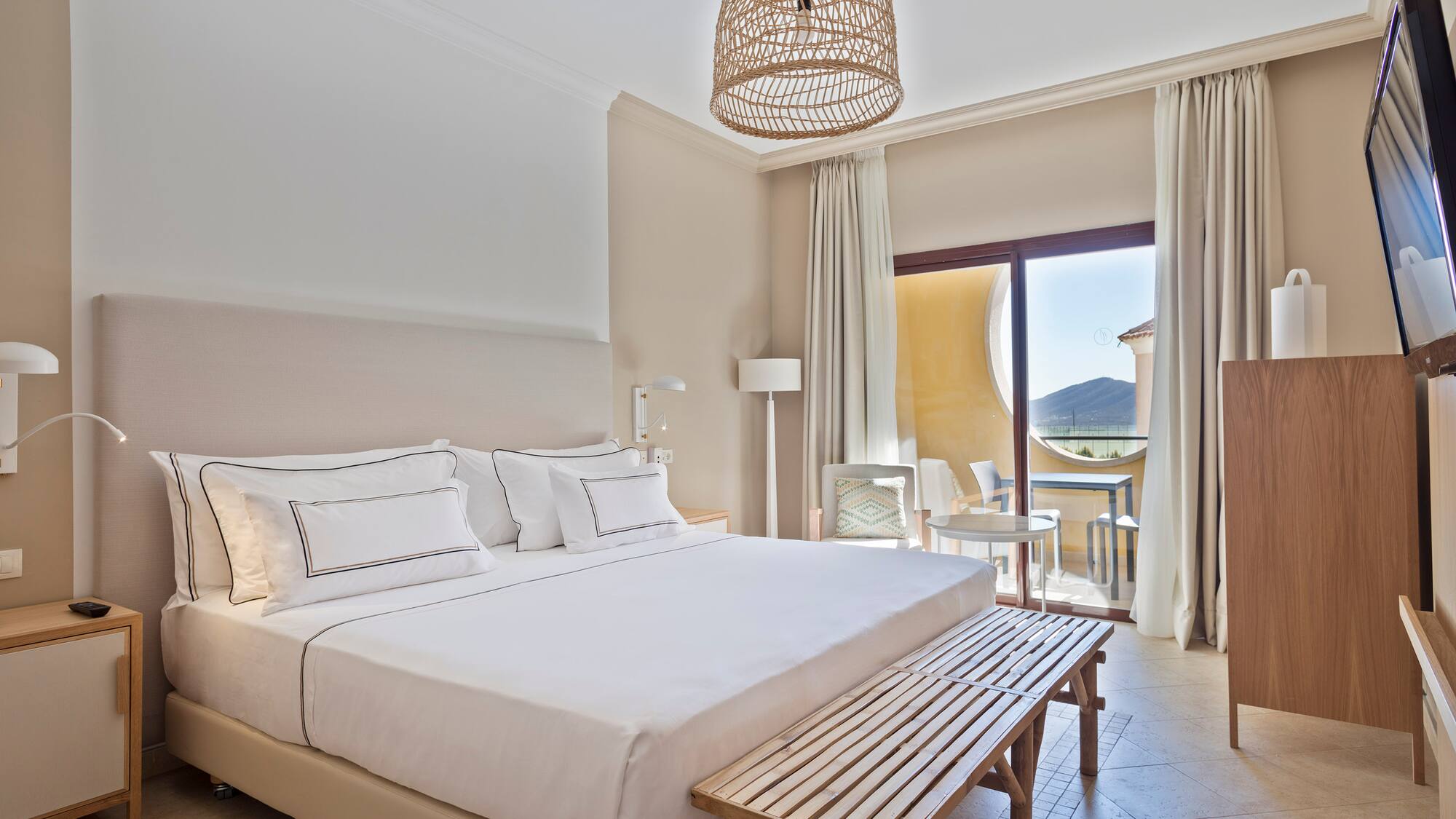 a bed with a bench and a table in a room with a balcony