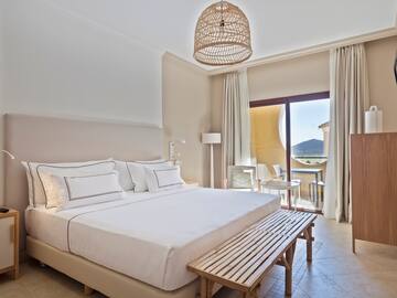 a bed with a bench and a table in a room with a balcony