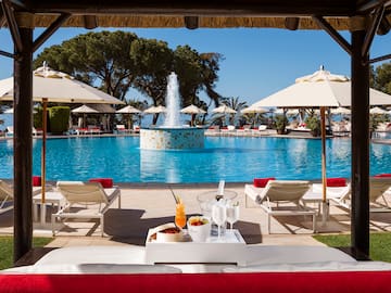 a pool with a fountain and a table with drinks