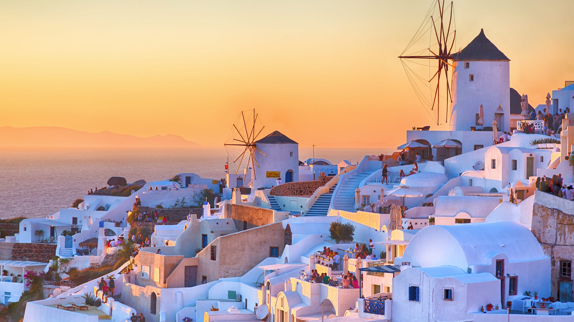 a white buildings with windmills on a hill