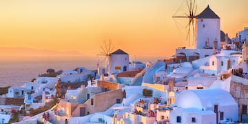a white buildings with windmills on a hill