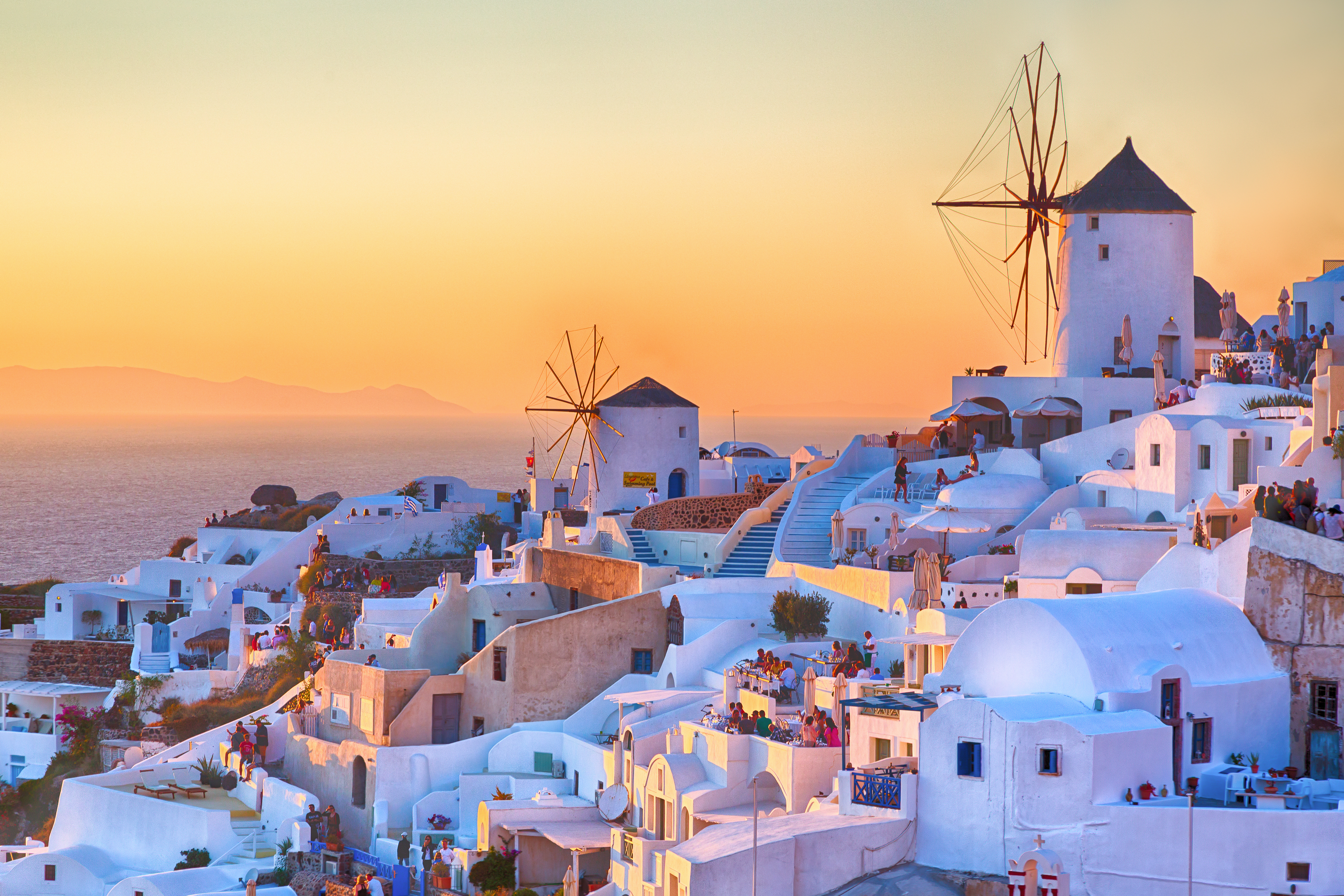 a white buildings with windmills on a hill