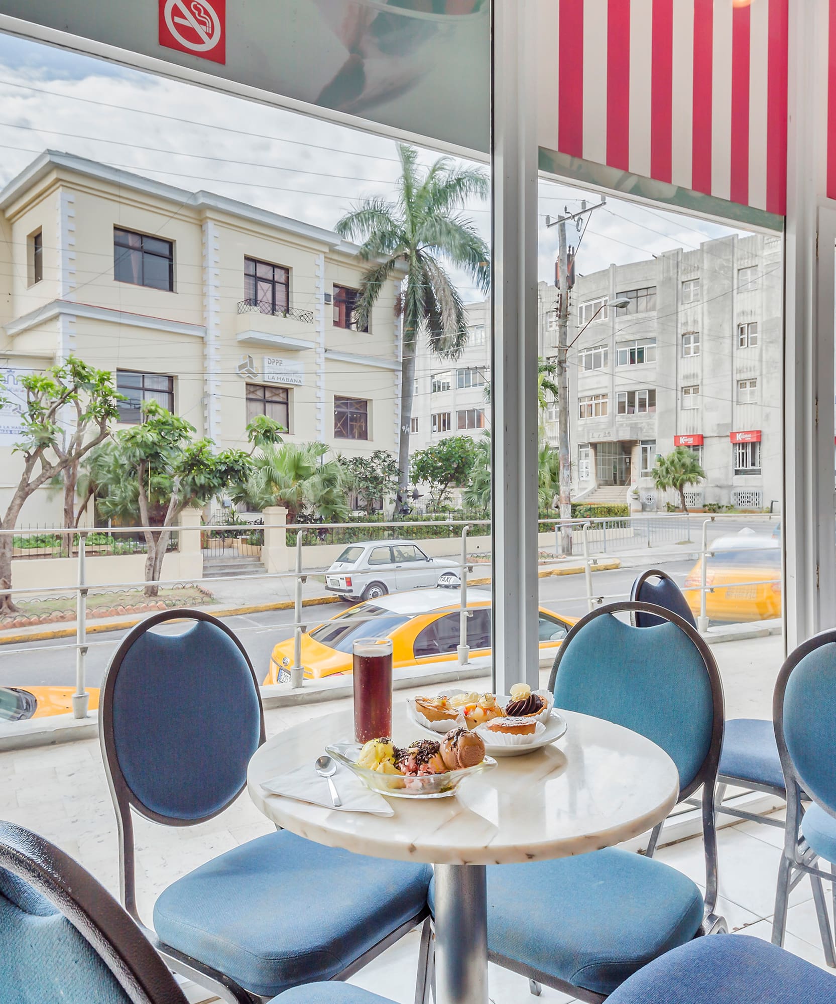 a table with food on it and blue chairs in front of a window