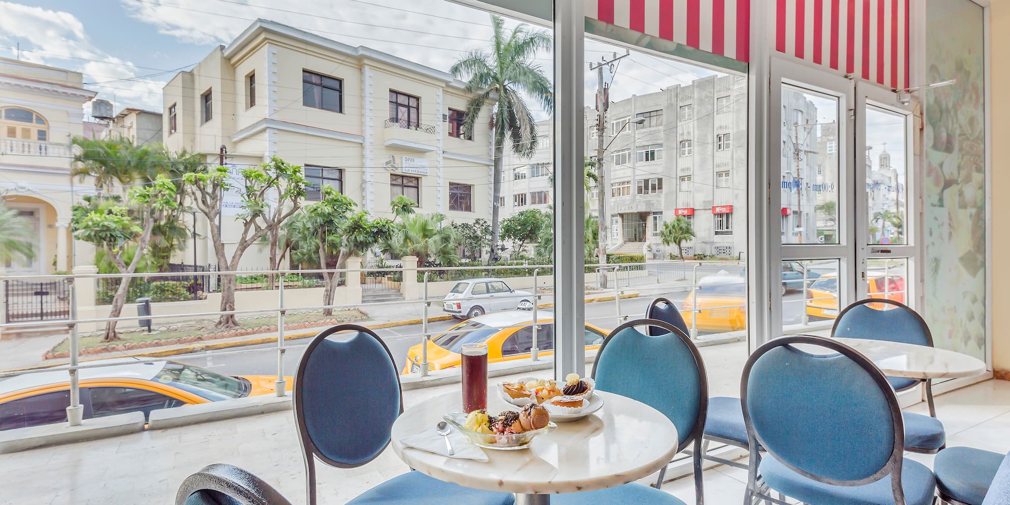 a table with food on it and blue chairs in front of a window