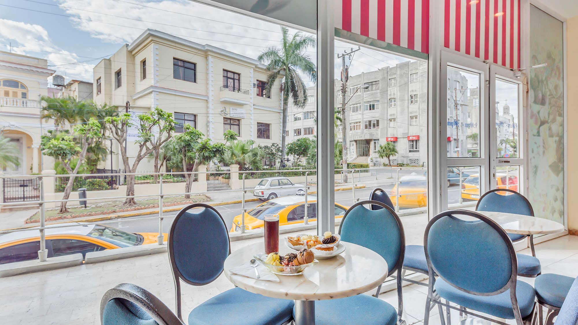 a table with food on it and blue chairs in front of a window