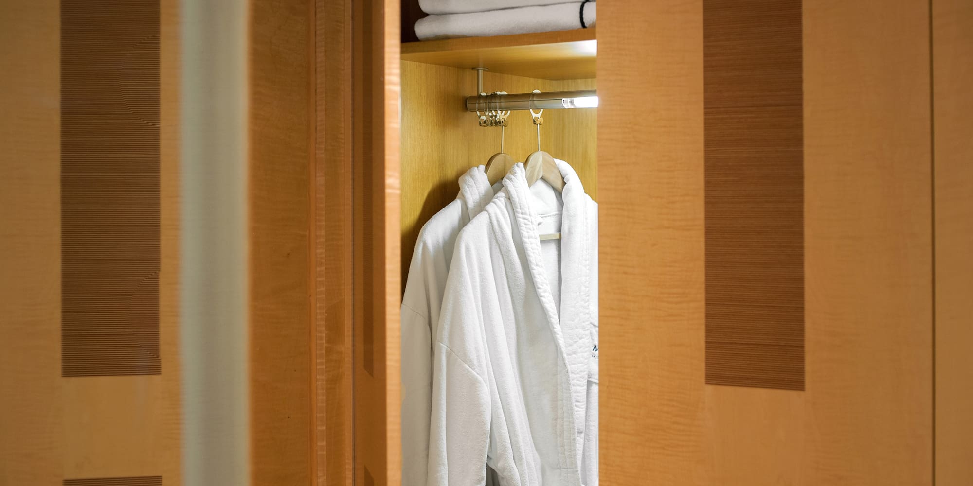 a closet with white bathrobes and towels