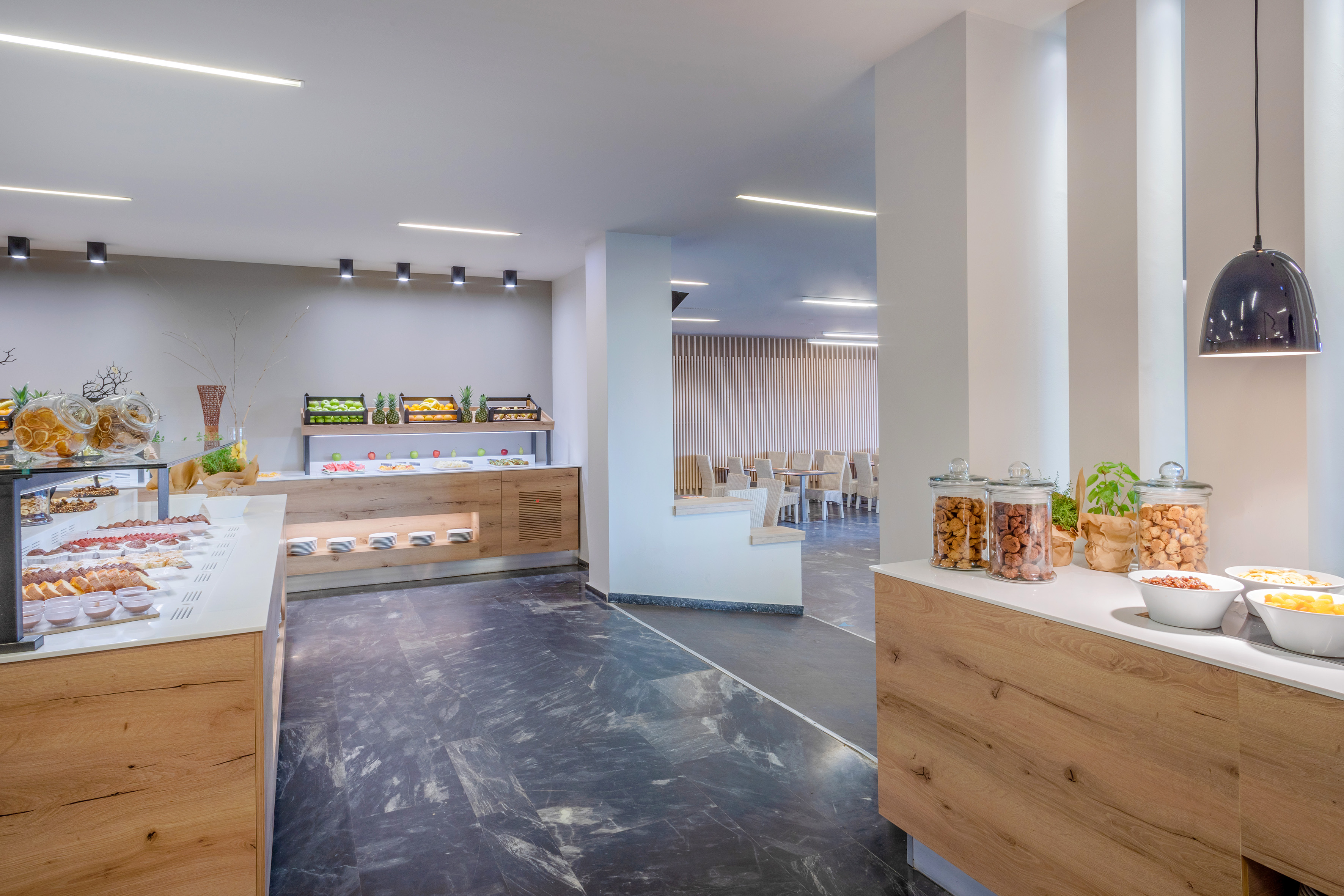 Modern hotel buffet with fresh fruit, pastries, and breakfast items.