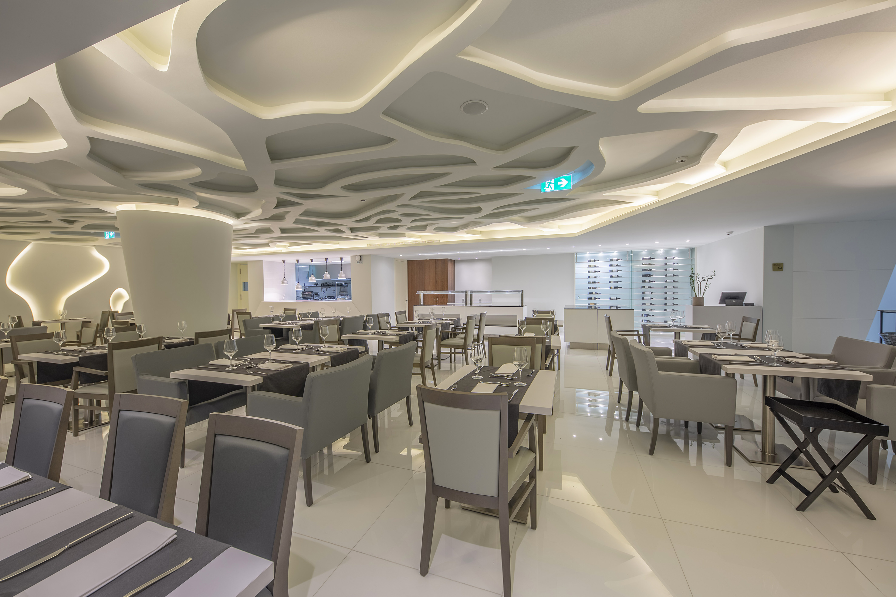 Modern hotel restaurant with abstract ceiling, buffet area, and set tables. - Lores, Internationale keuken - Meliá Maputo Sky, Maputo
