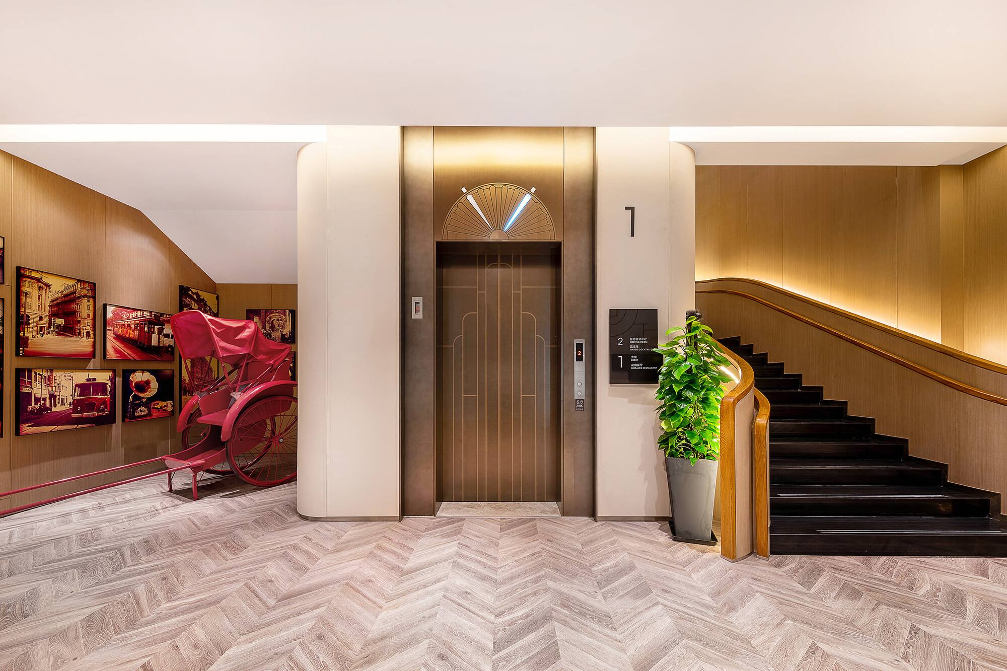Hotel lobby: modern elevator, dark staircase, herringbone floor, red rickshaw.