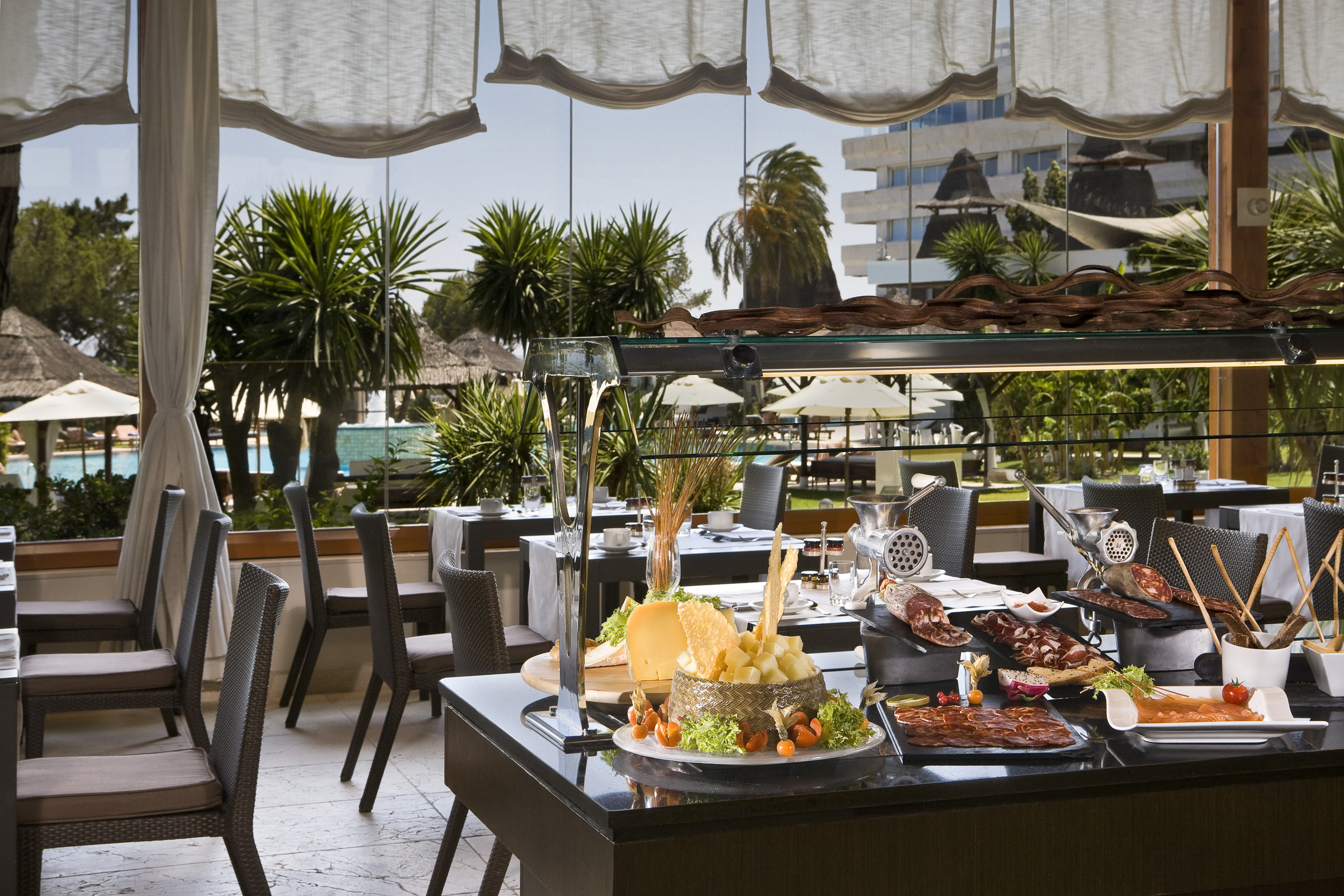 Resort restaurant buffet with cold cuts, cheese, and tropical pool view.
