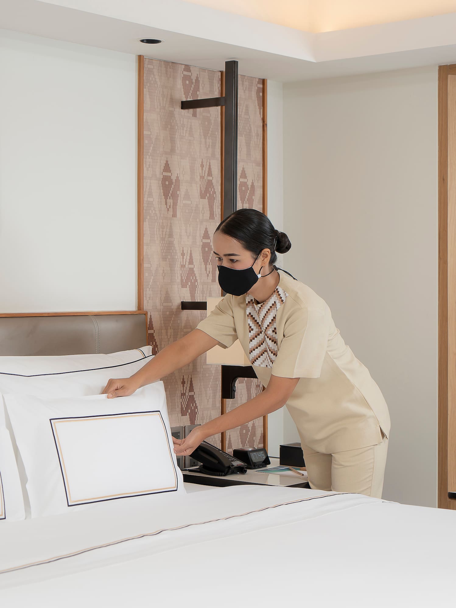 a woman wearing a mask and putting a bed on