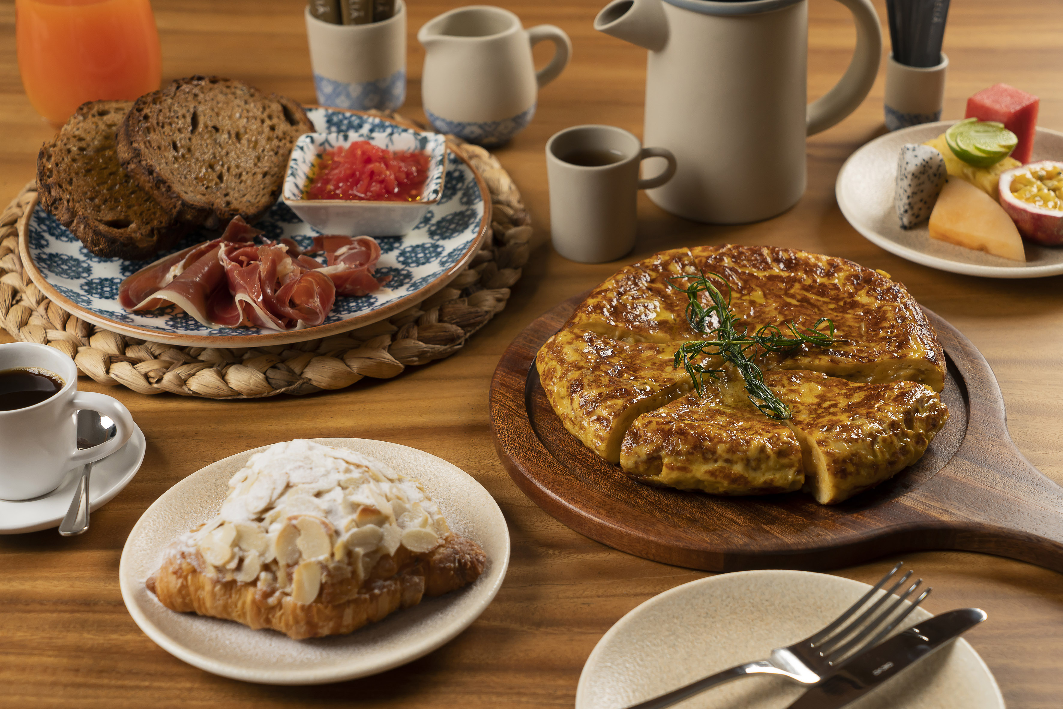 Spanish breakfast: tortilla, cured ham, bread, croissant, fresh fruit, coffee.