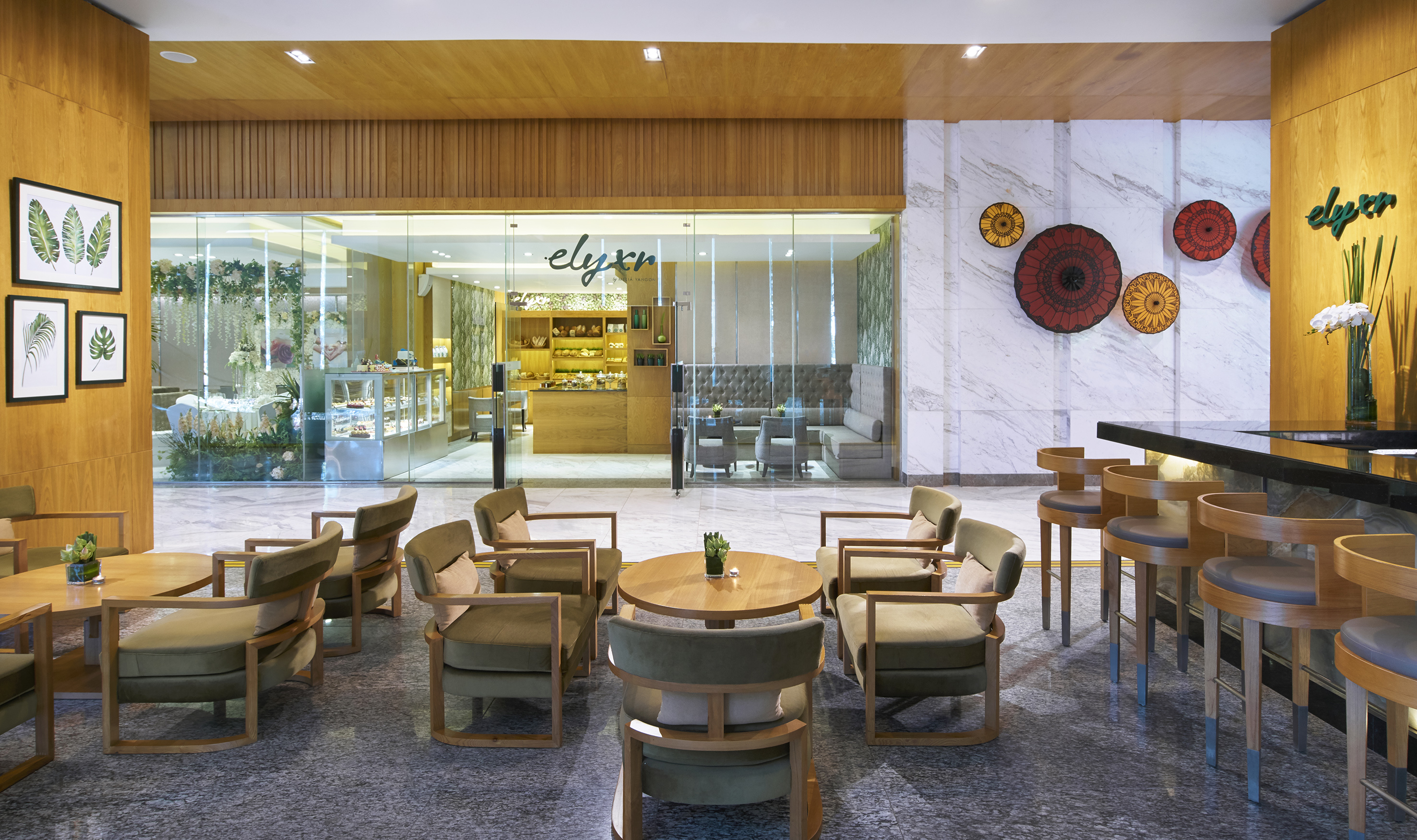 Modern hotel lounge with Elyxr cafe entrance, bar, and elegant seating.
