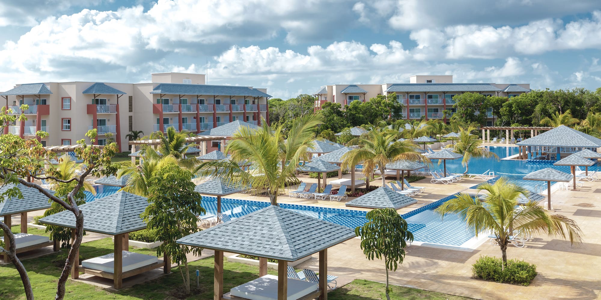 a pool with lounge chairs and trees in front of buildings