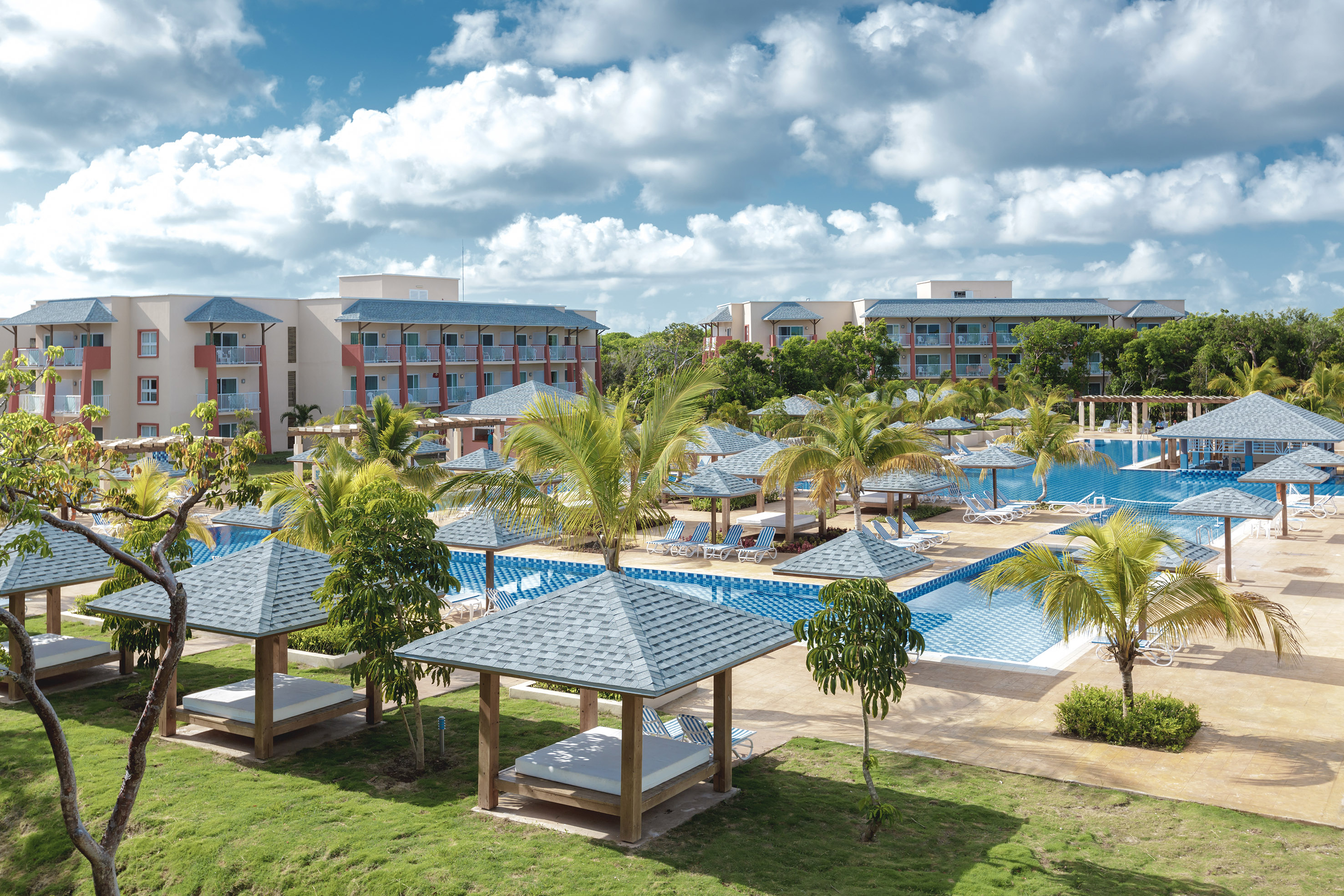 a pool with lounge chairs and trees in front of buildings