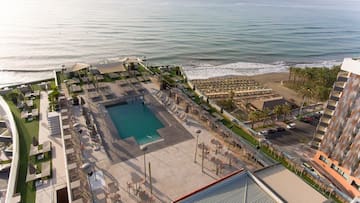 a pool and chairs on a rooftop overlooking a beach