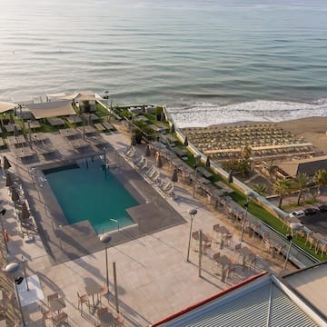 a pool and chairs on a rooftop overlooking a beach