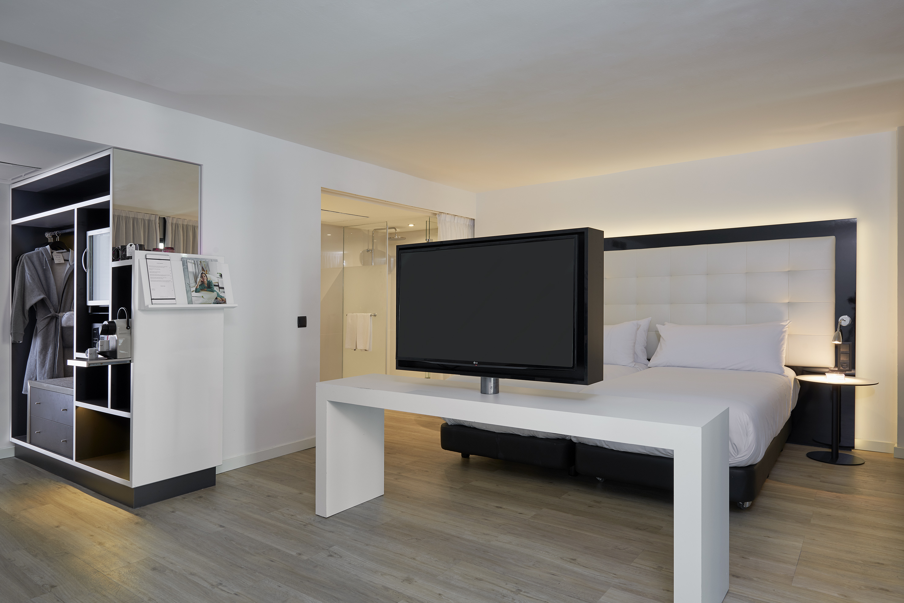 Modern hotel room with a large bed, flat-screen TV, and open wardrobe.