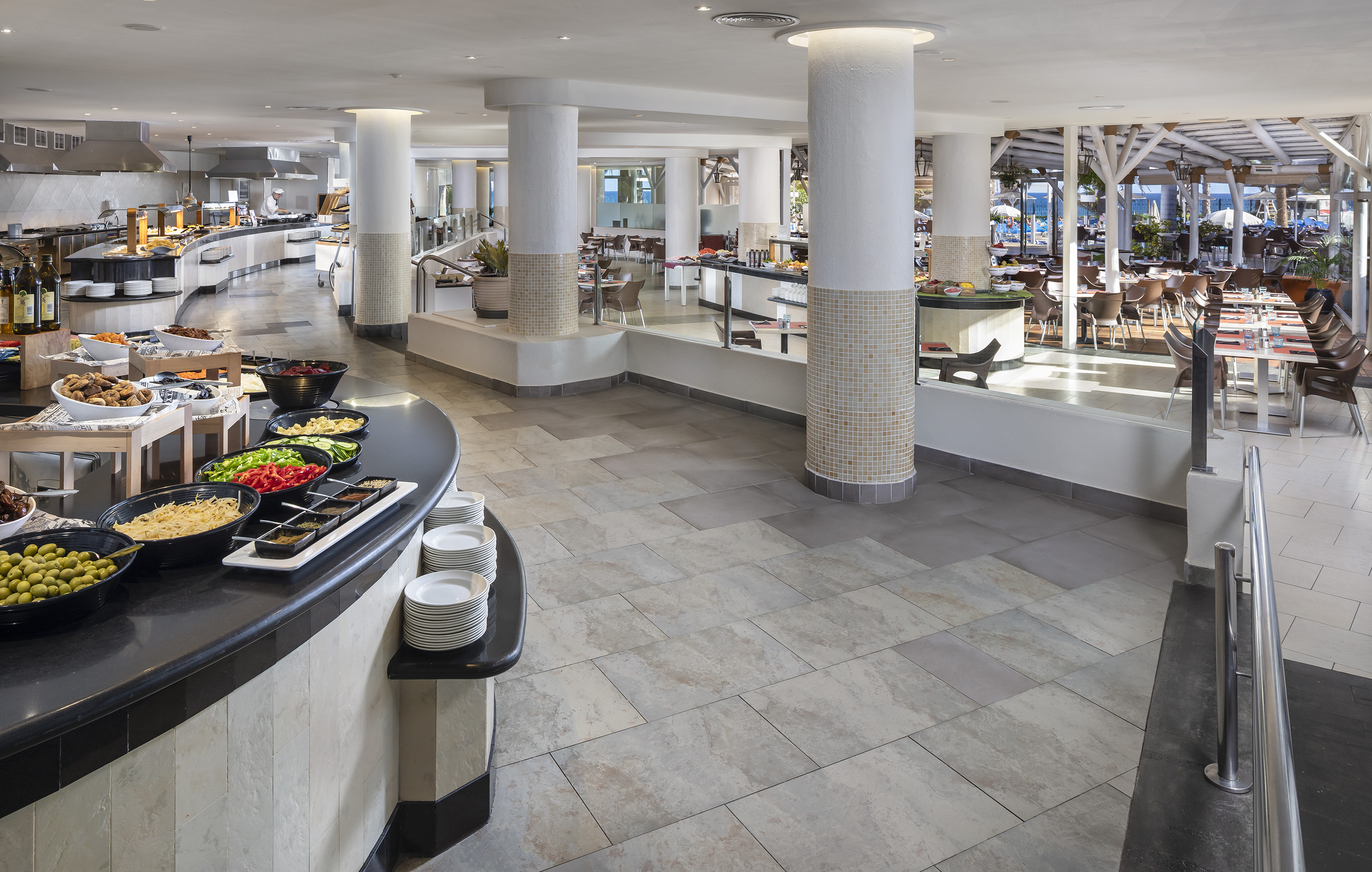 Spacious hotel buffet restaurant with multiple food stations and outdoor seating.