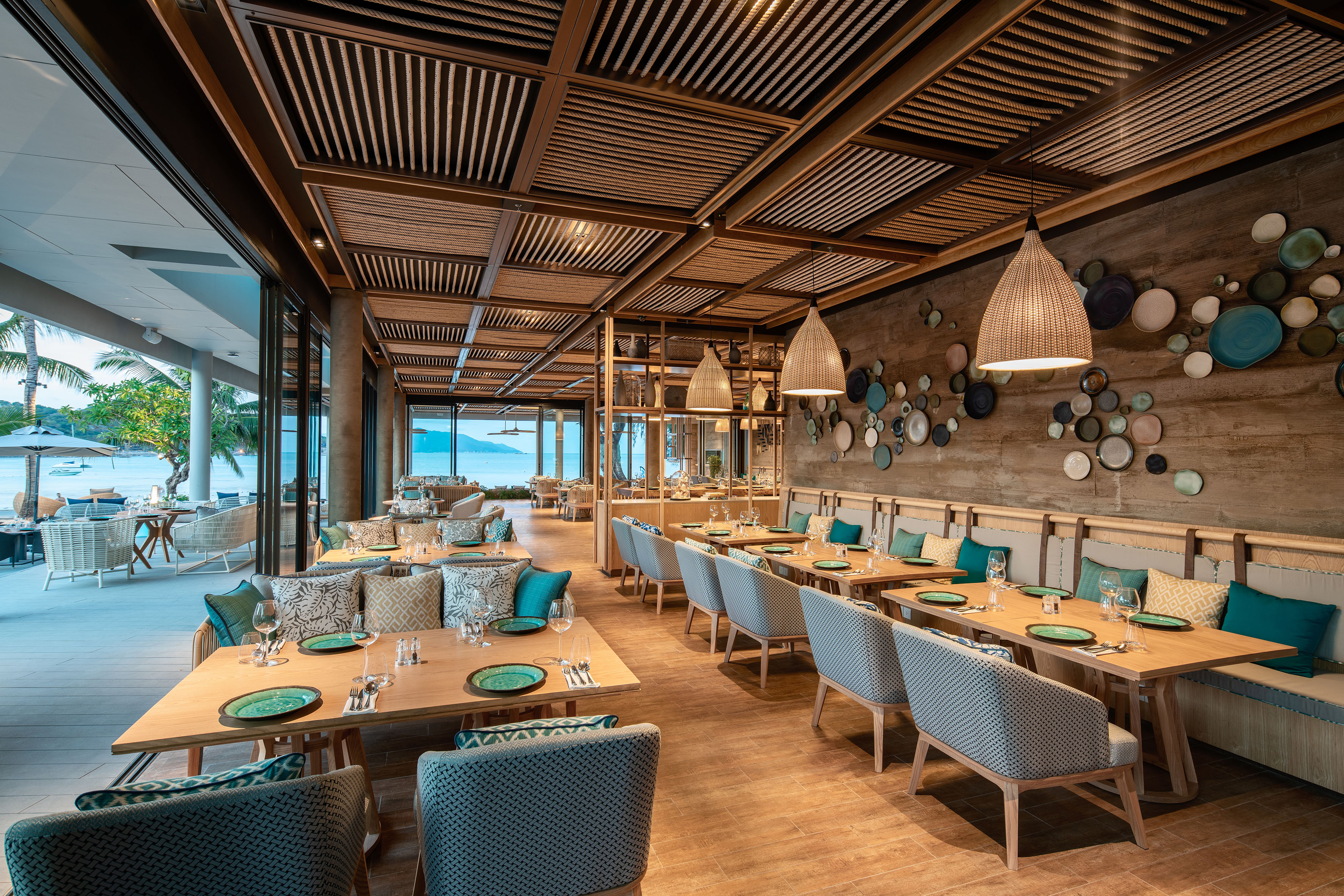 Luxury beachfront restaurant with ocean view and modern tropical decor.