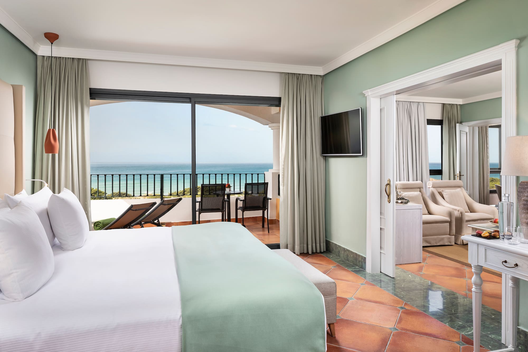 a room with a bed and a balcony overlooking the ocean