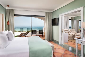 a room with a bed and a balcony overlooking the ocean