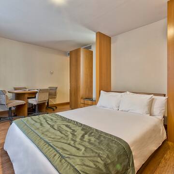 a bed with a green blanket and a desk in a room