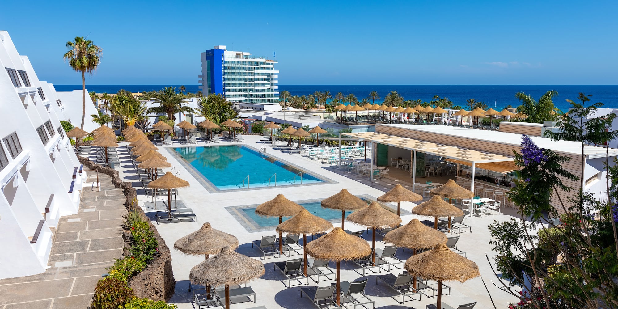a pool with umbrellas and chairs by a building