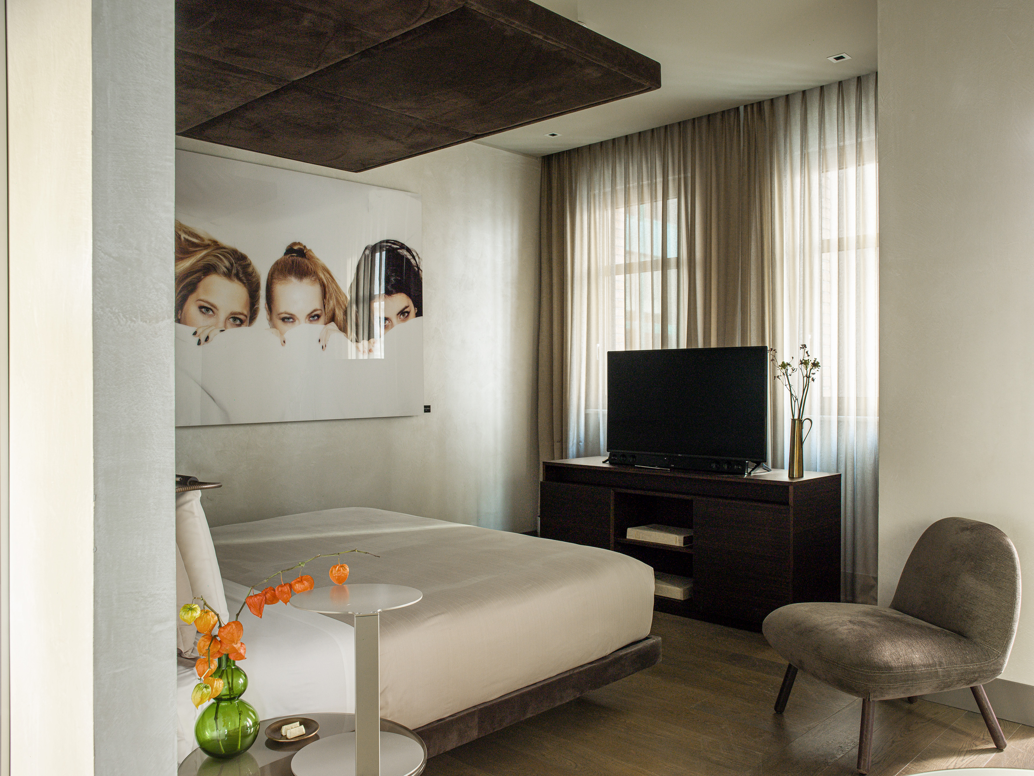 Modern bedroom interior with large bed, wall art, TV, and neutral decor.