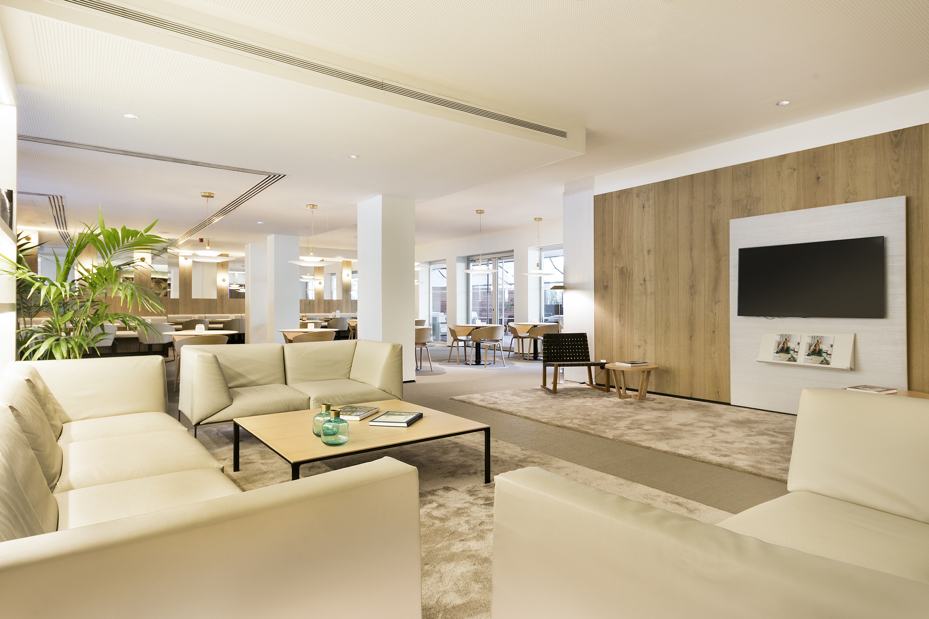 Spacious modern hotel lounge with cream sofas and wood accent wall.