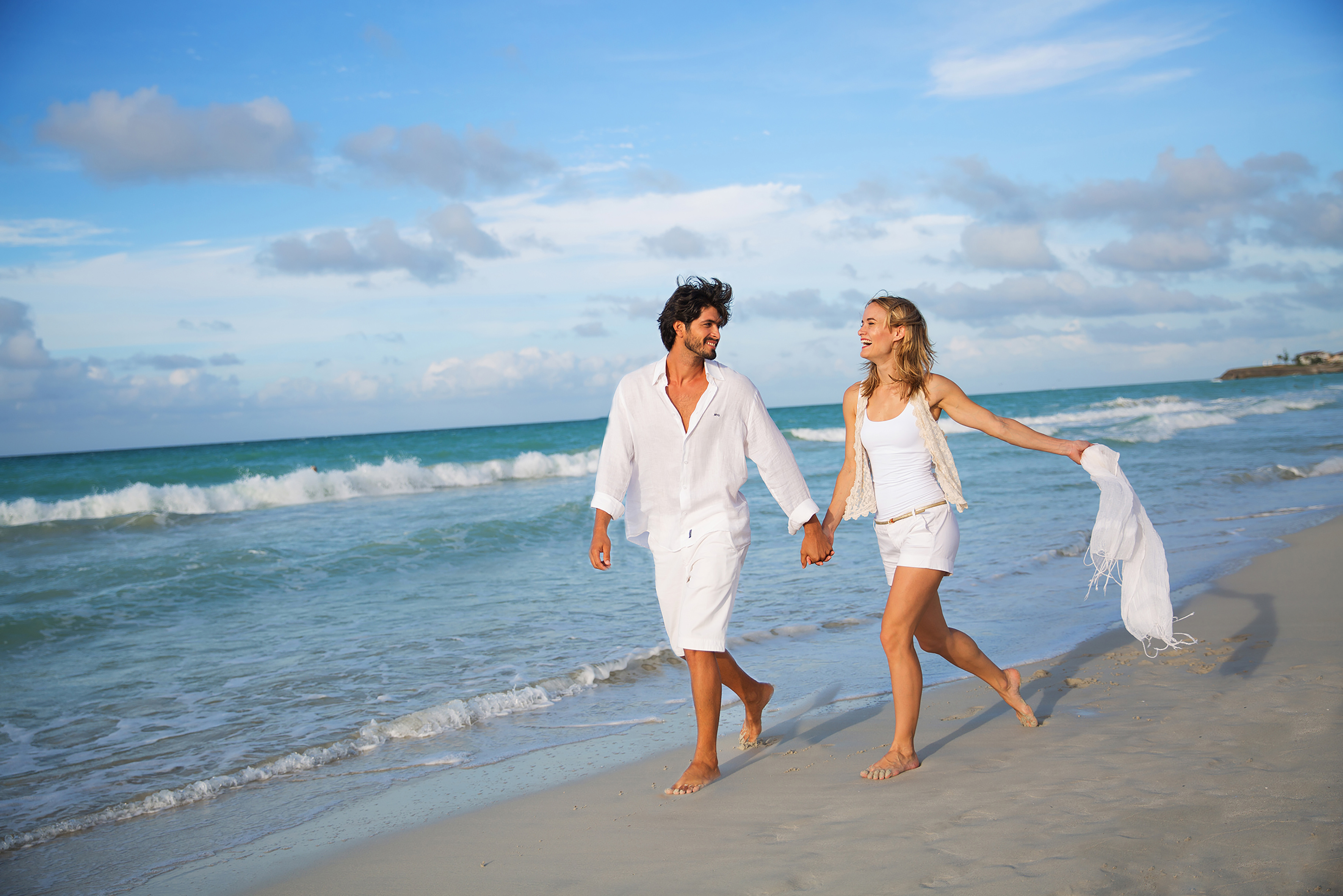 a man and woman holding hands on a beach