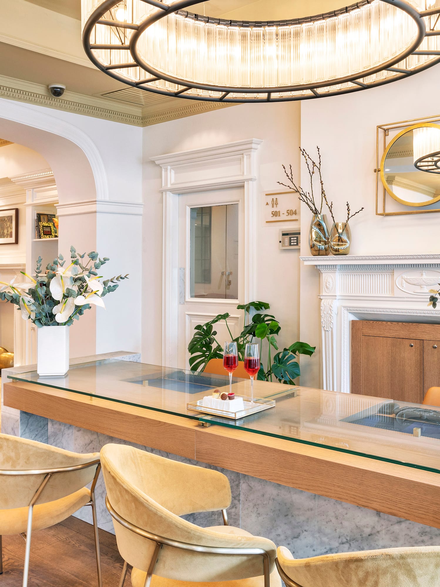 Elegant serviced apartment lobby with glass reception desk and velvet chairs.