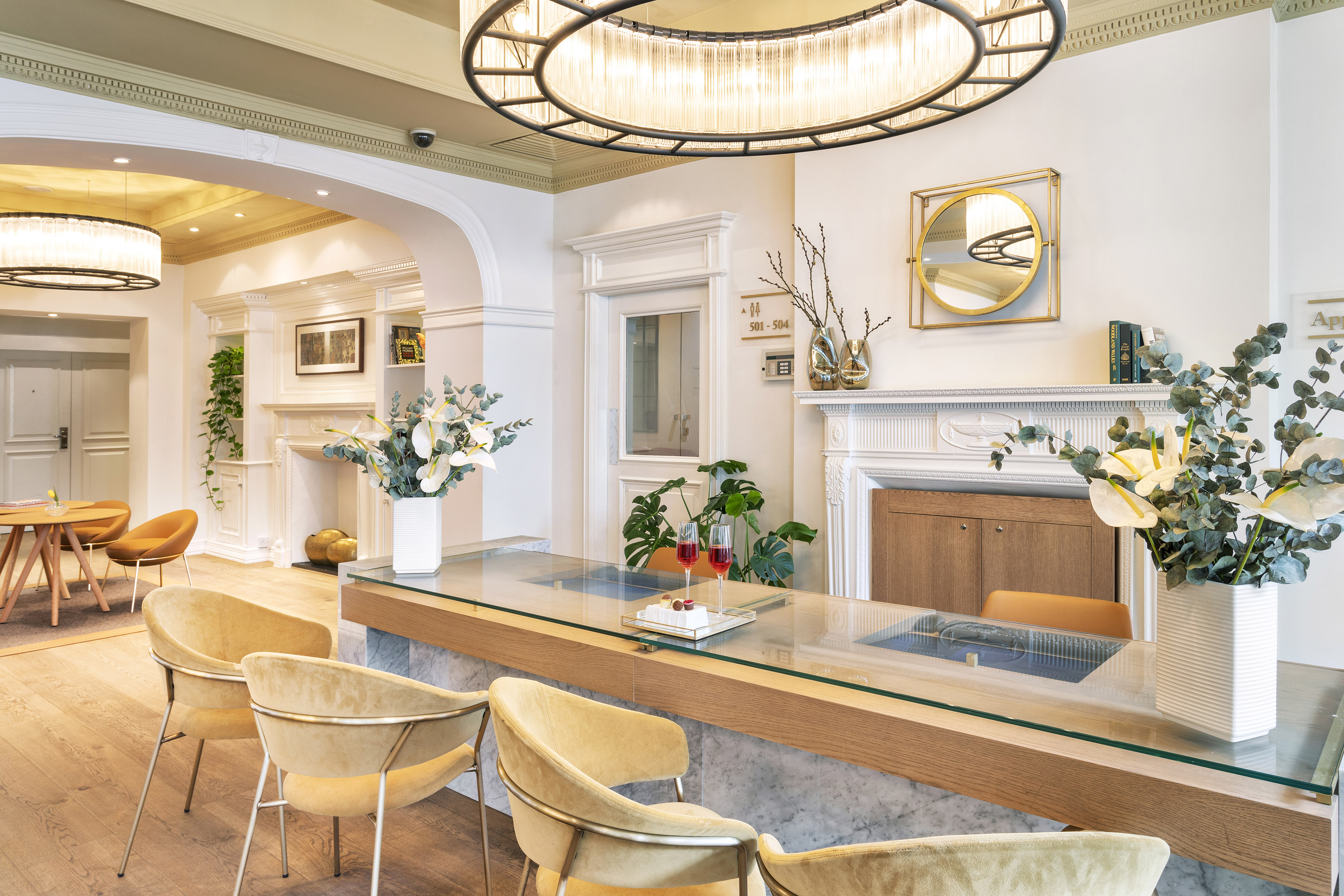 Elegant serviced apartment lobby with glass reception desk and velvet chairs.